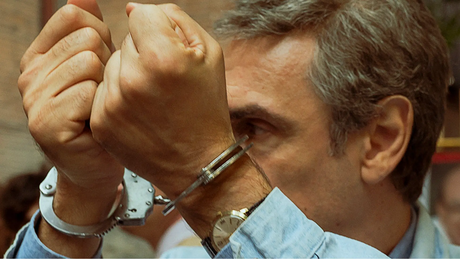 Fabrizio Gifuni as Enzo Tortora in Portobello raises handcuffed wrists in the series’ signature image..Courtesy: Warner Bros. Discovery / HBO Max.