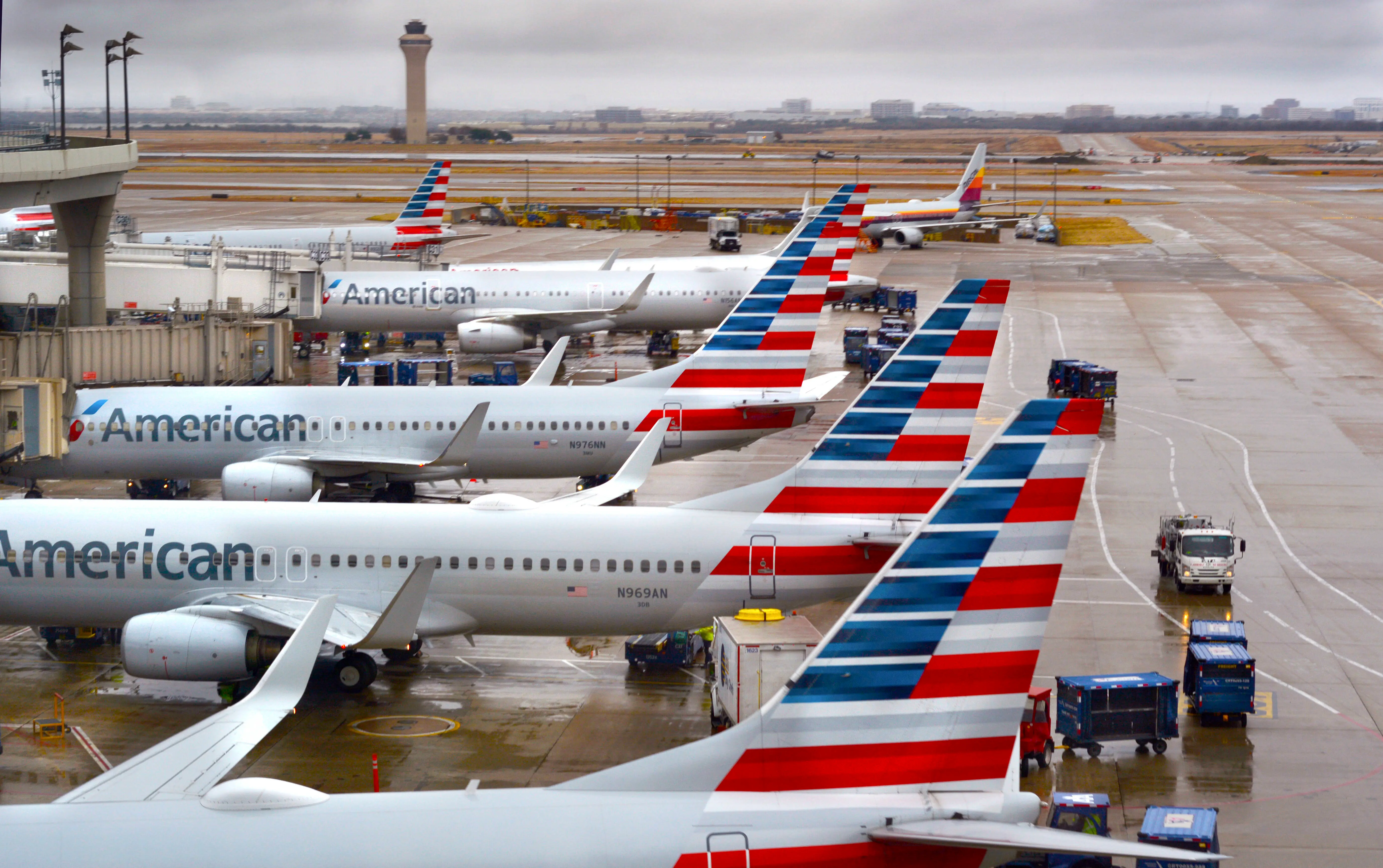 American Airlines passenger jets parked at their gates on a rainy morning at Dallas/Fort Worth International Airport which serves the Dallas/Fort Worth, Texas, metroplex area in Texas (Image via Getty)
