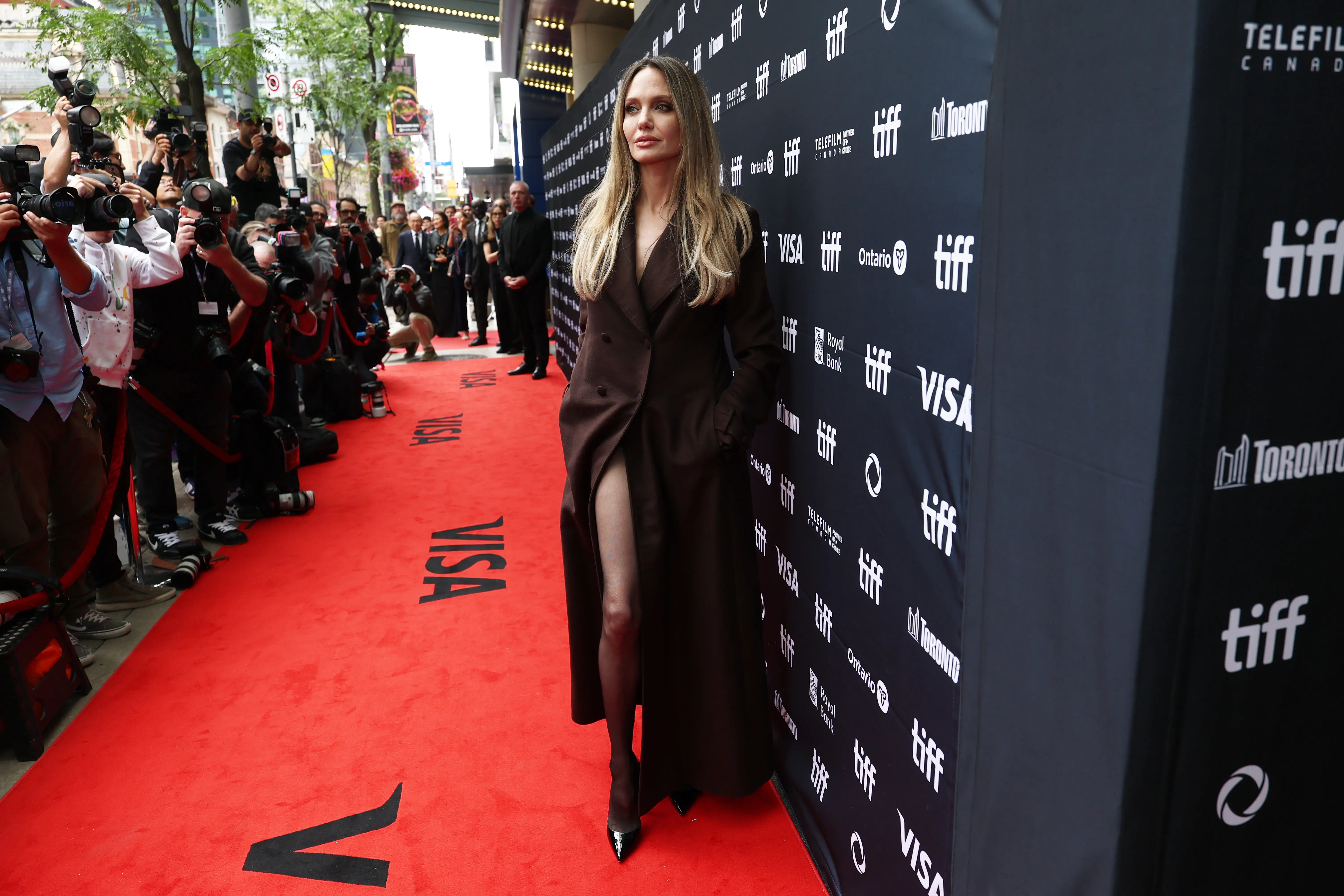 Angelina Jolie revisits her 2012 Oscars moment with a striking slit-coat look at the 2025 TIFF red carpet.
