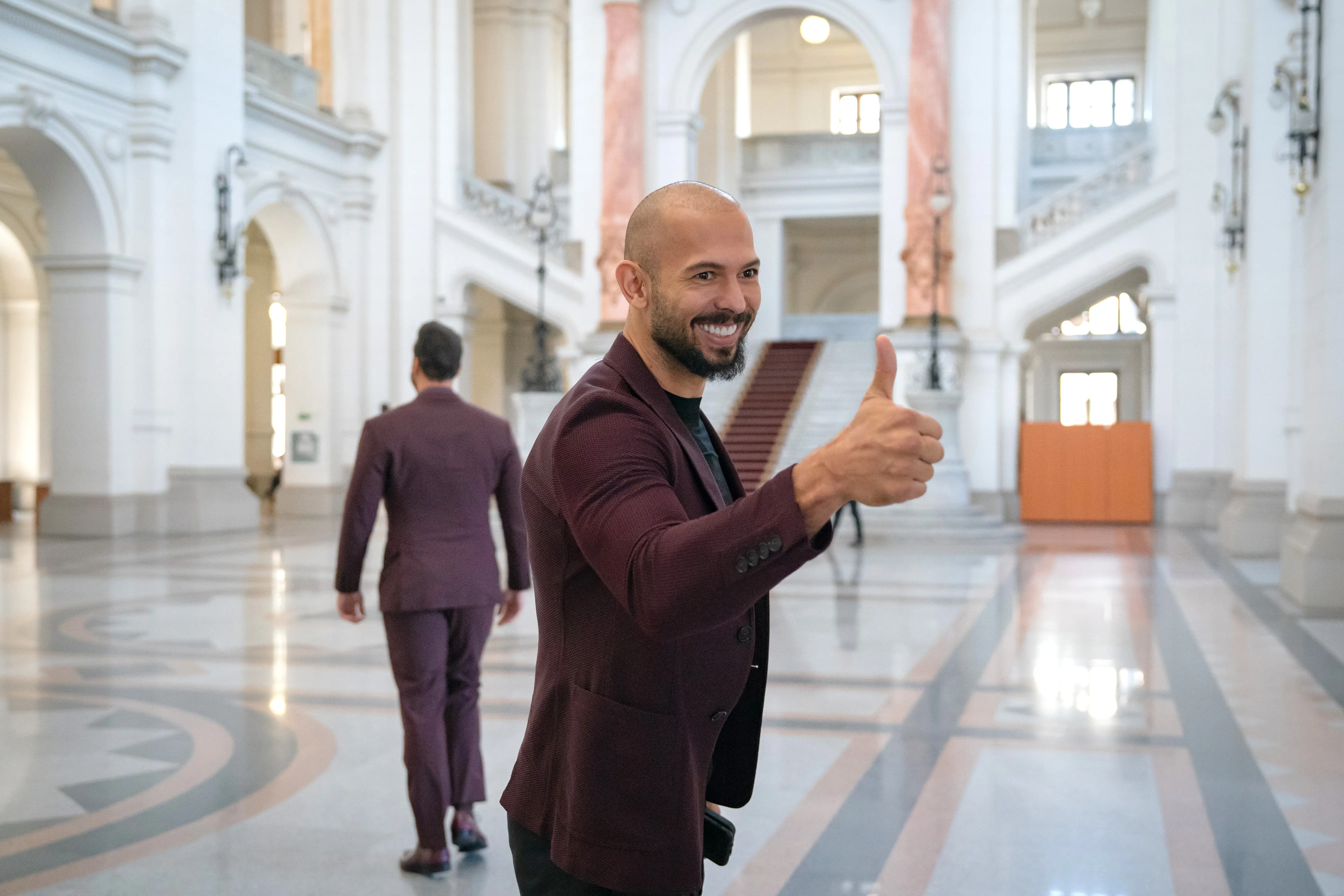 BUCHAREST, ROMANIA - OCTOBER 15: Andrew Tate (left) poses for a photo while entering the Court of Appeal on October 15, 2024 in Bucharest, Romania. Social Media Influencer Andrew Tate and his brother Tristan are appearing in court to appeal a decision to proceed with their trial on charges of rape, human trafficking and forming a criminal gang to exploit women. The Tate brothers were arrested on December 29, 2022, alongside Georgiana Naghel and Luana Radu as part of an investigation into human trafficking and rape. (Photo by Andrei Pungovschi/Getty Images)