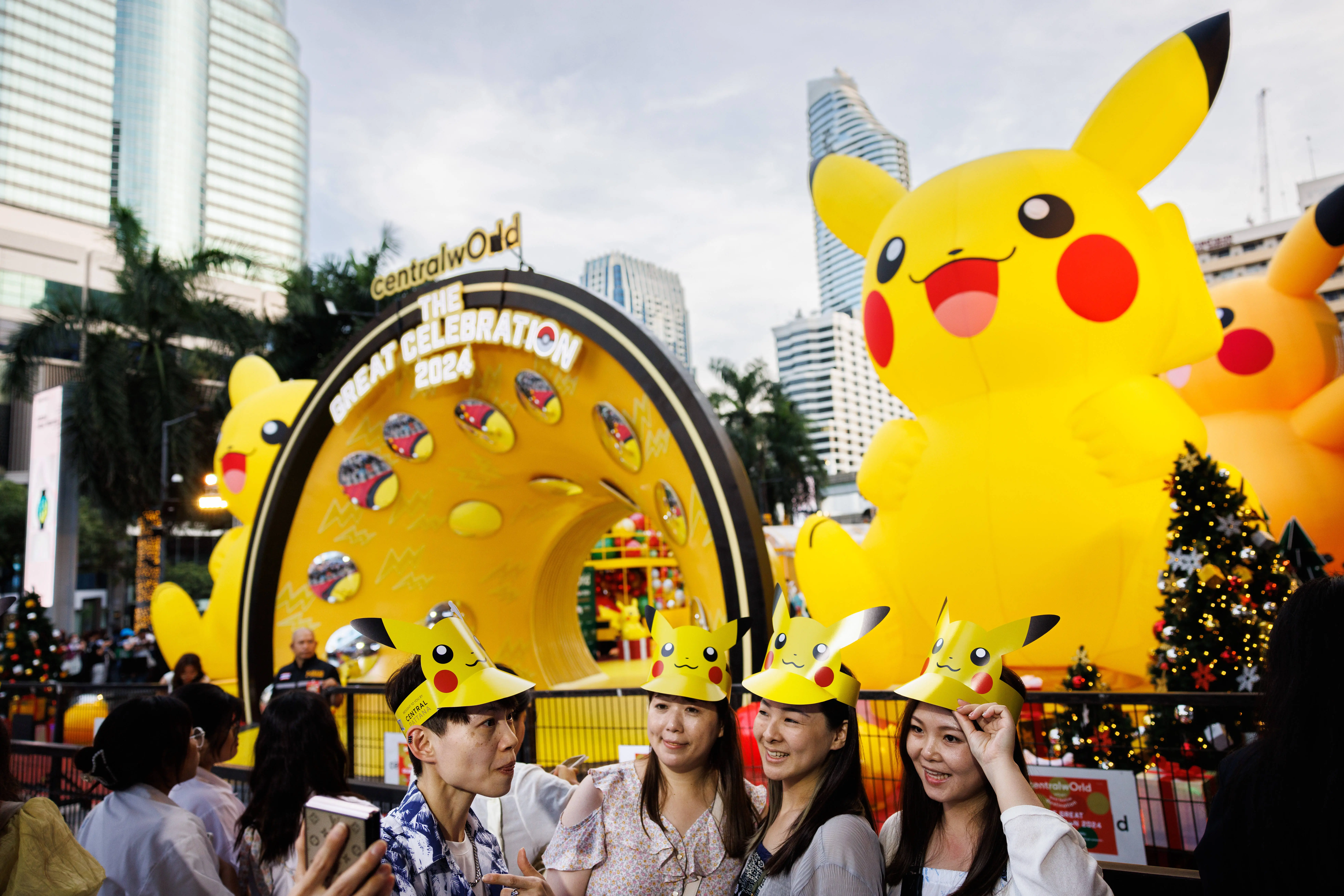 BANGKOK, THAILAND - NOVEMBER 27: Pokemon fans wear Pikachu hats and take selfies in front of a giant inflatable Pikachu at Central World Shopping Mall during a holiday kick off event on November 27, 2023 in Bangkok, Thailand. Featuring the largest Pokemon takeover in Southeast Asia, Central World Shopping Center hosts its "Light Up Christmas Tree Celebration" to kick off the holiday season. The celebration includes 30 dancing Pikachus, a 15-meter-tall inflatable Pikachu, and other Pokemon characters placed around Thailand's tallest Christmas tree, which is decorated with thunderbolts. (Photo by Lauren DeCicca/Getty Images)