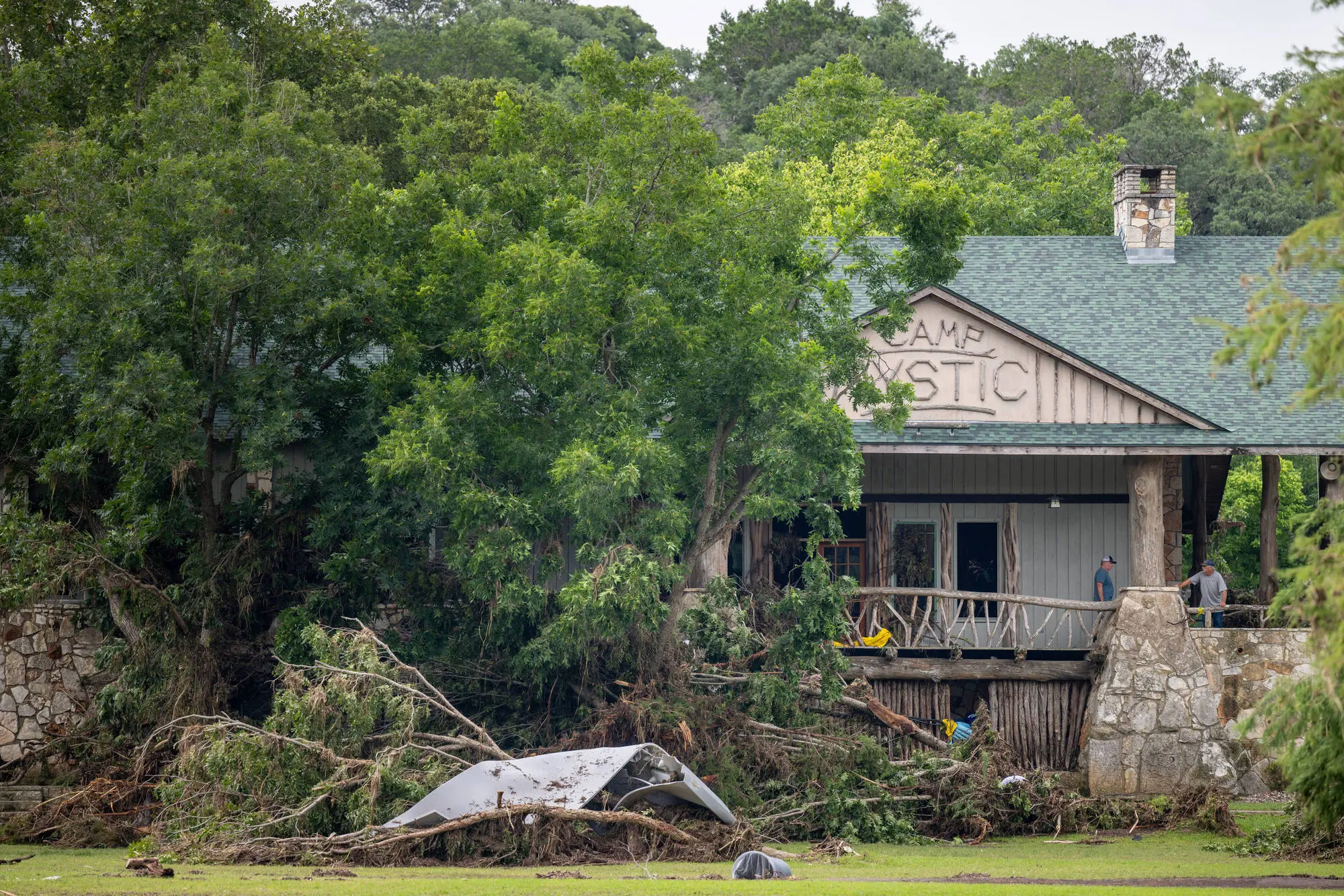 Debris is piled up at the entrance to Camp Mystic on July 07, 2025 in Hunt, Texas (Image via Getty)