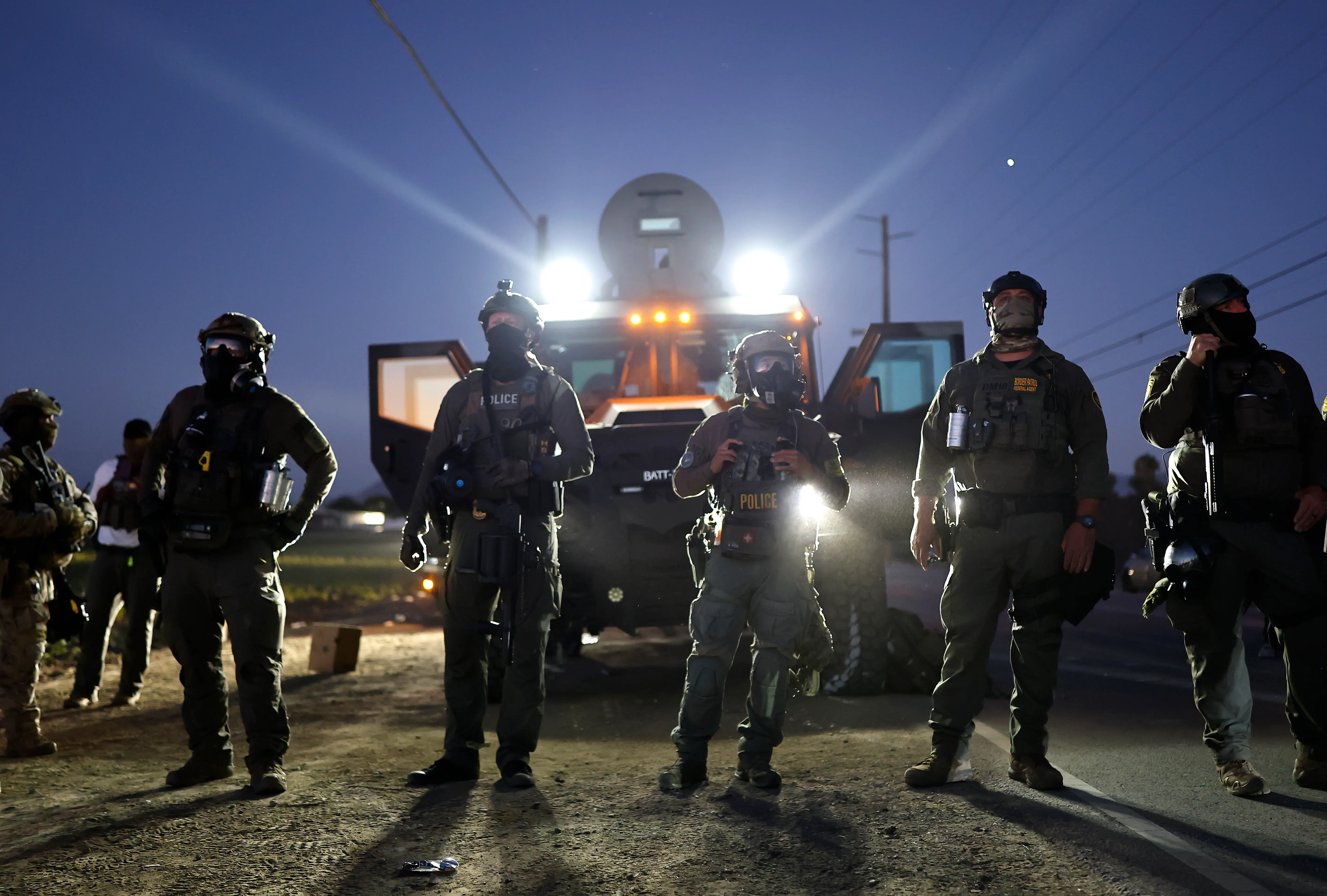 CAMARILLO, CALIFORNIA - JULY 10:  Federal agents block people protesting an ICE immigration raid at a nearby licensed cannabis farm on July 10, 2025 near Camarillo, California. Protestors stood off with federal agents for hours outside the farm in the farmworker community in Ventura County. A Los Angeles federal judge is set to rule Friday on a temporary restraining order which would restrict area immigration enforcement operations. (Photo by Mario Tama/Getty Images)