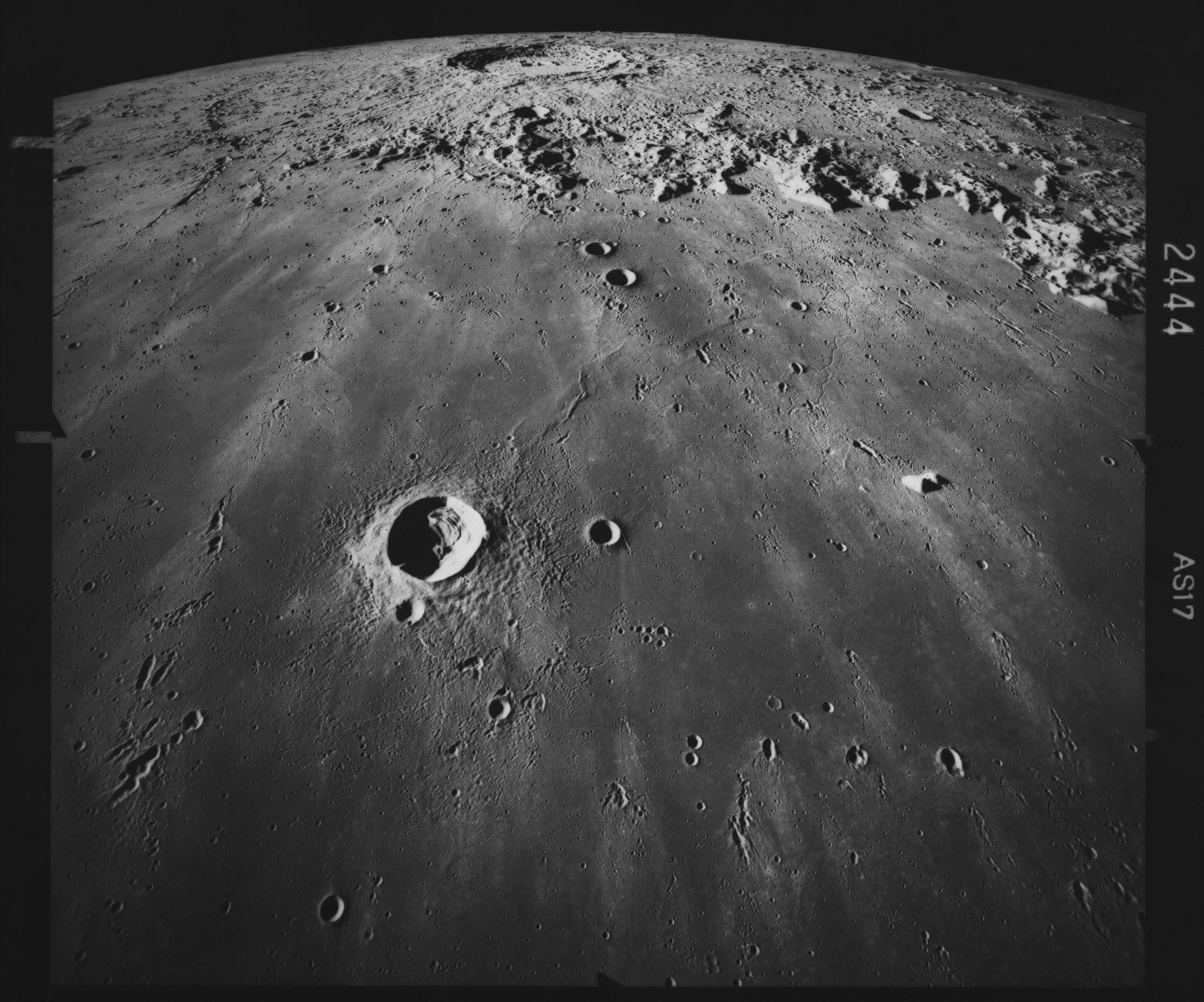 Image of the lunar surface, looking south across Mare Imbrium, with the crater Copernicus (58 miles in diameter) visible in the distance, in an image of the lunar surface taken during the Apollo 17, 7th to 19th December 1972. Crater Pytheas (12 miles in diameter) is visible in the foreground, with several chains of small craters beyond, these are oriented toward Copernicus and are secondary craters produced by material ejected when Copernicus formed. (Photo by Space Frontiers/Archive Photos/Hulton Archive/Getty Images)