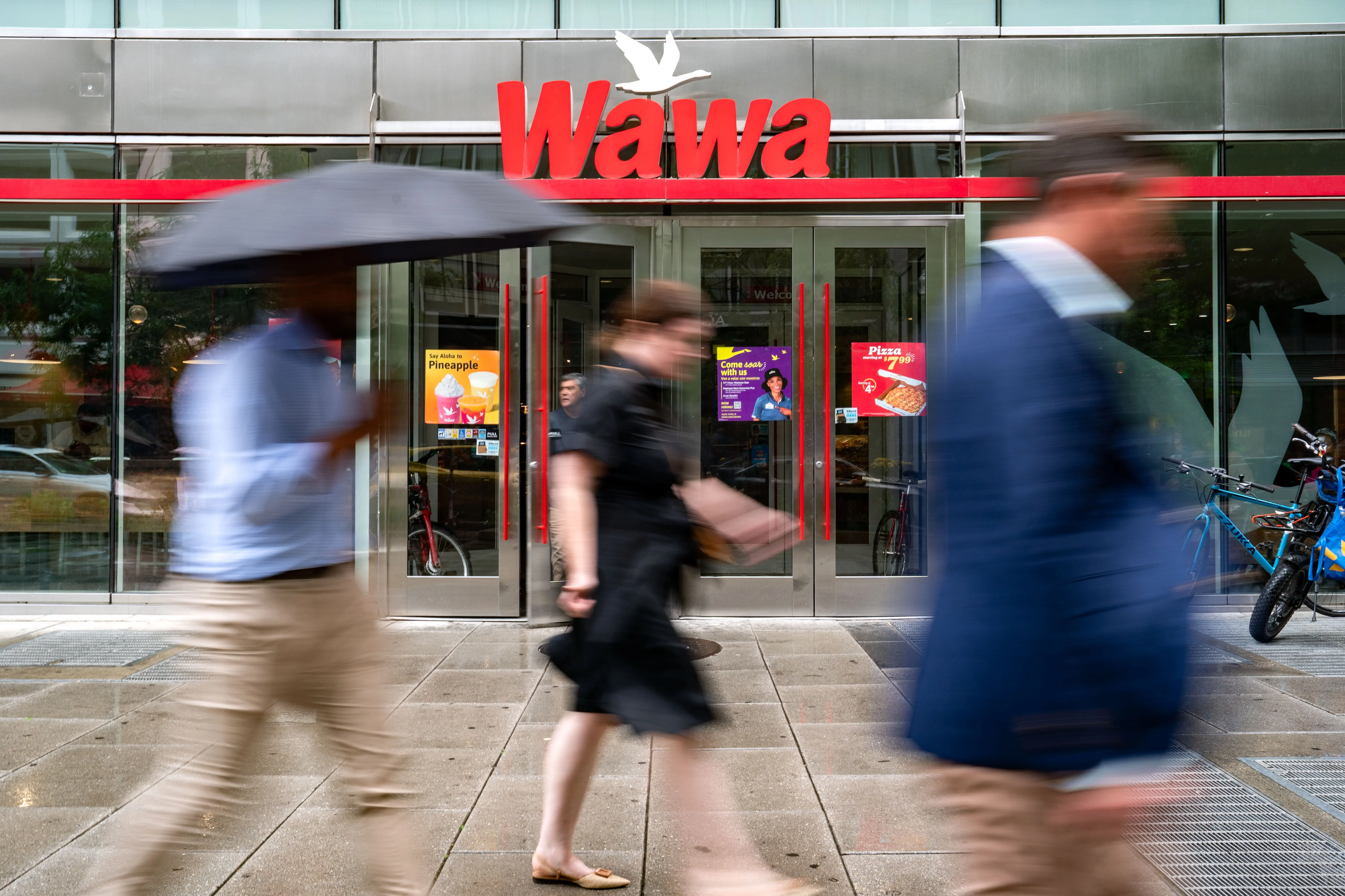 WASHINGTON, DC - MAY 29: People walk past a Wawa store on May 29, 2024 in Washington, DC. The convenience store and gas station chain, which has its origins in Pennsylvania, recently opened its first store in North Carolina, with 10 more expected across the state this year. It aims to open up to 100 new stores each year, reaching 2,000 stores by 2030. (Photo by Kent Nishimura/Getty Images)