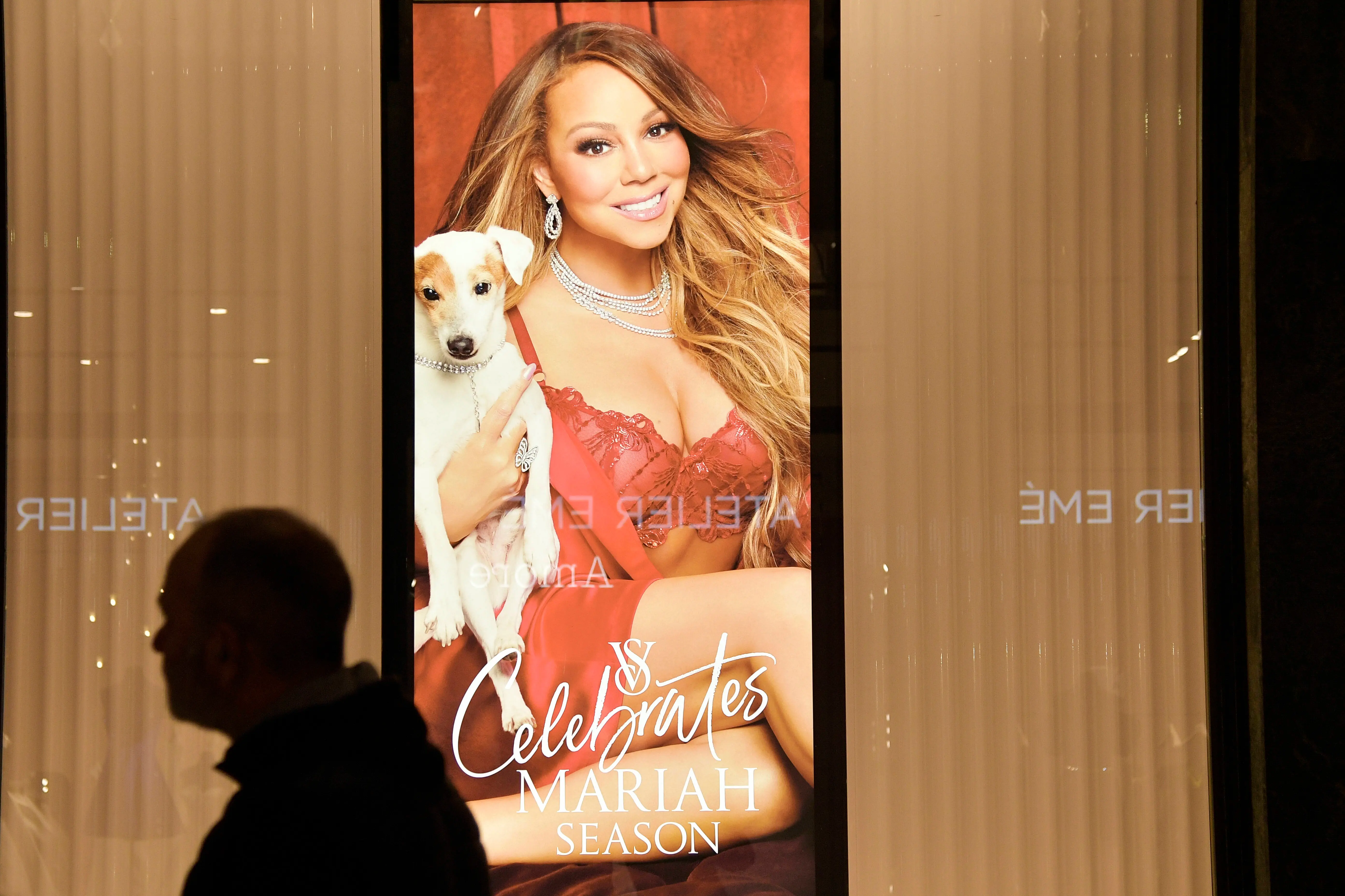 A man walks in front of a Mariah Carey poster in the window of American lingerie chain Victoria's Secret during the holiday shopping season on December 13, 2023 in Turin, Italy. (Photo by Stefano Guidi/Getty Images)