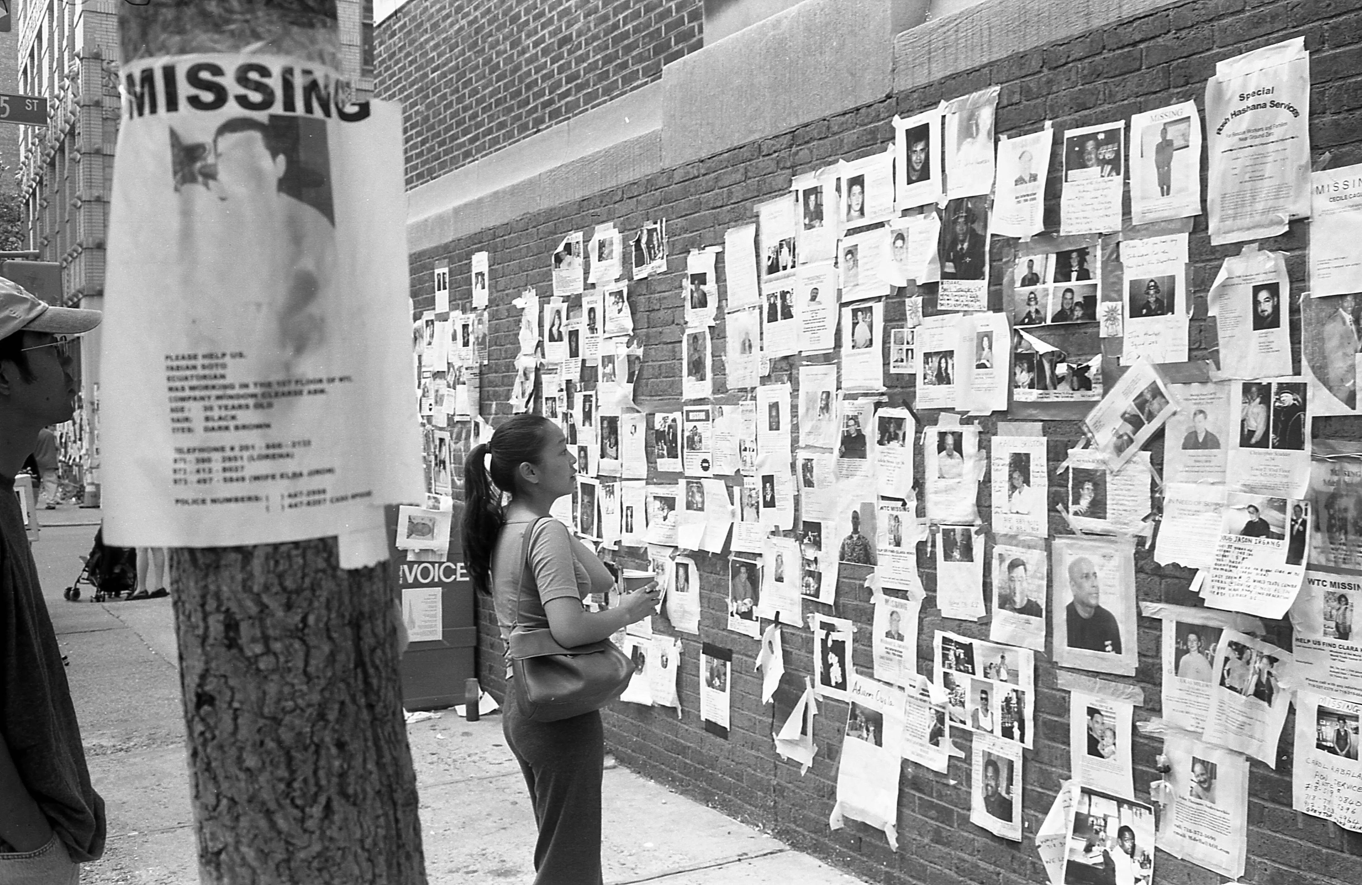 View of pedestrians as they look at pictures of people missing after the September 11 terrorist attacks, on a wall on 3rd Avenue (at East 25th Street), in the Kips Bay neighborhood, New York, New York, September 22, 2001. (Photo by Walter Leporati/Getty Images)