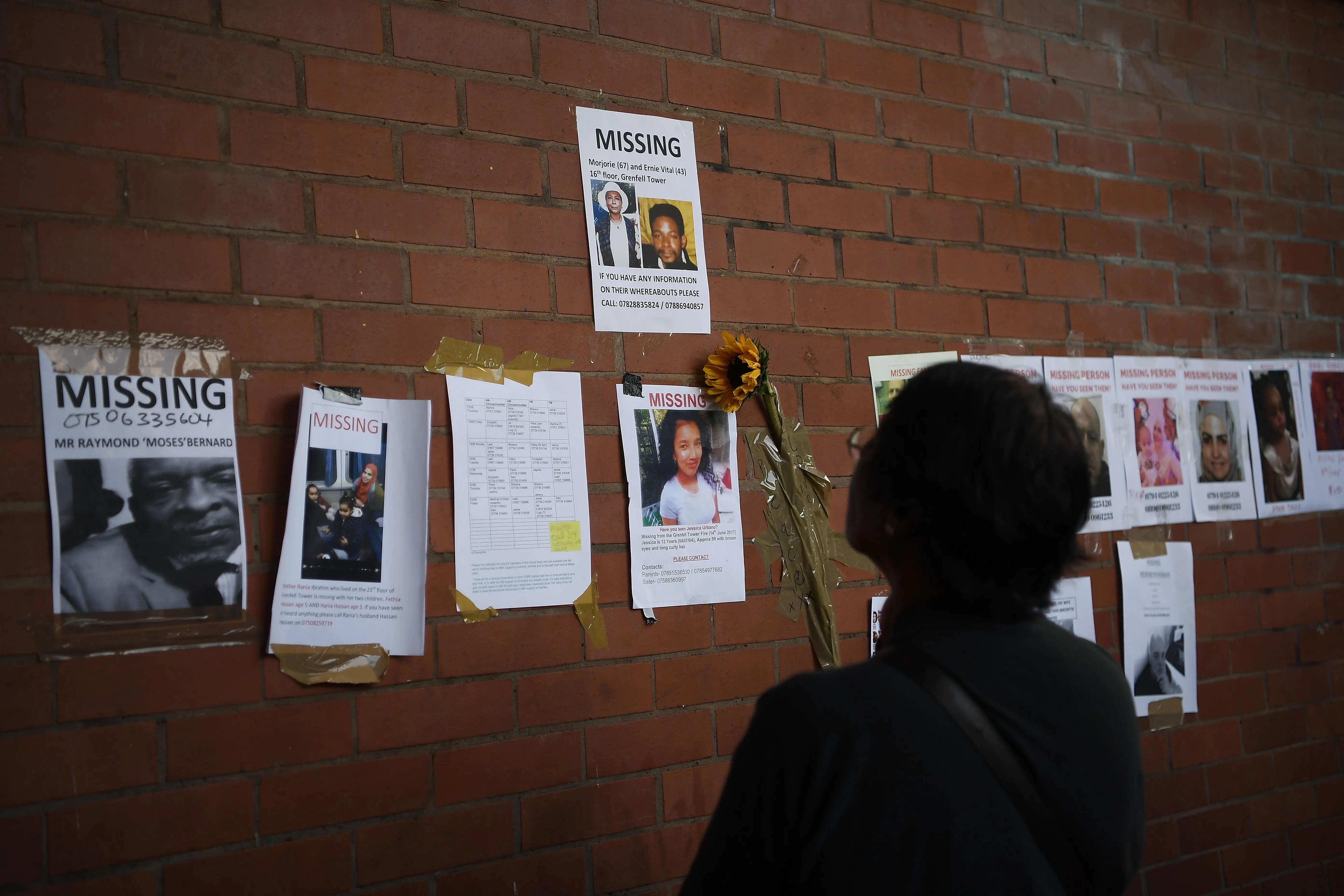 LONDON, ENGLAND - JUNE 16:  A member of the community looks at missing person posters near Grenfell Tower on June 16, 2017 in London, England. 30 people have been confirmed dead and dozens still missing after the 24 storey residential Grenfell Tower block in Latimer Road was engulfed in flames in the early hours of June 14. Emergency services will spend a third day searching through the building for bodies. Police have said that some victims may never be identified.  (Photo by Carl Court/Getty Images)
