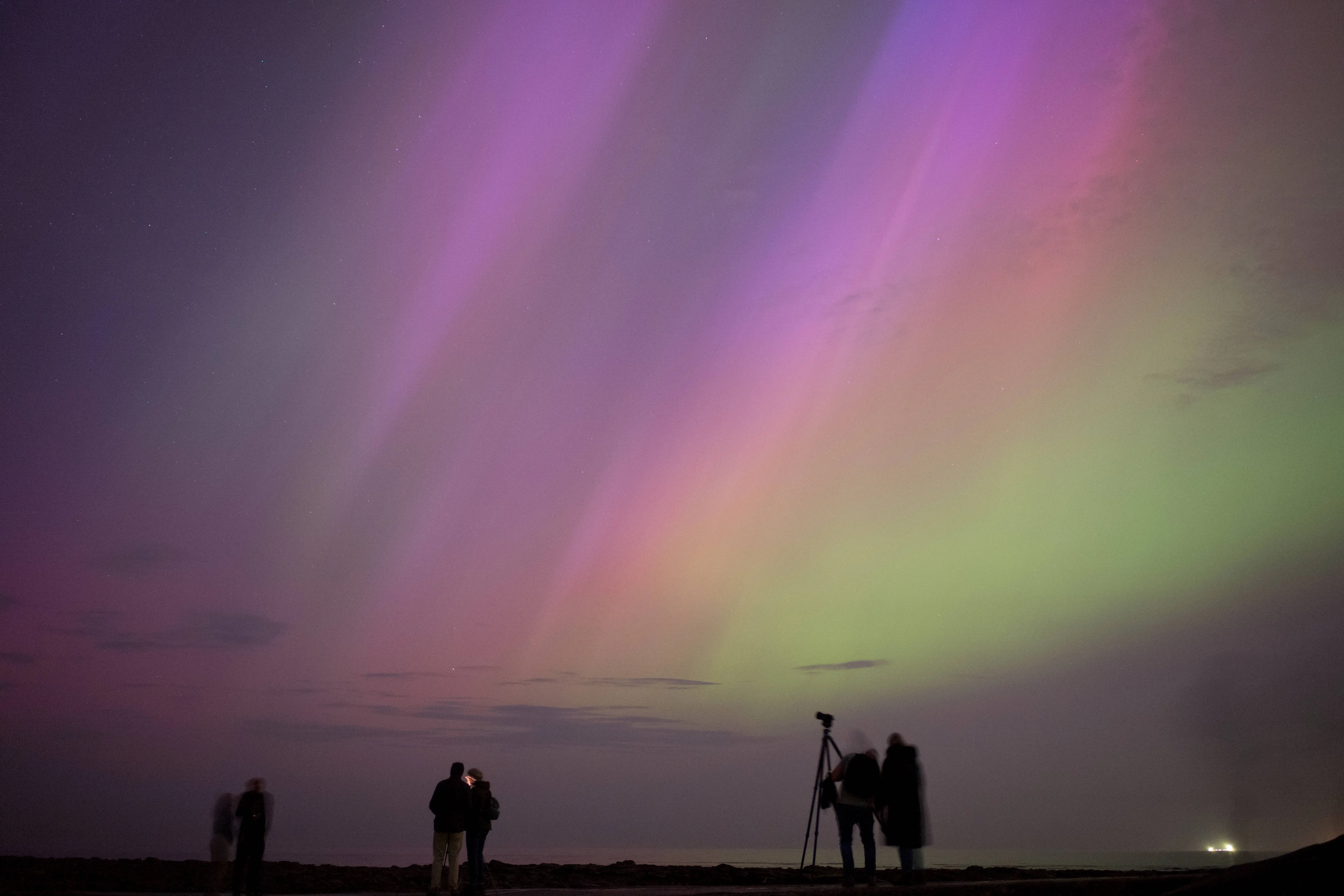 WHITLEY BAY, ENGLAND - MAY 10: People visit St Mary's lighthouse in Whitley Bay to see the aurora borealis, commonly known as the northern lights, on May 10, 2024 in Whitley Bay, England. The UK met office said a strong solar storm may allow northern parts of the UK the chance to see displays of aurora.  (Photo by Ian Forsyth/Getty Images)