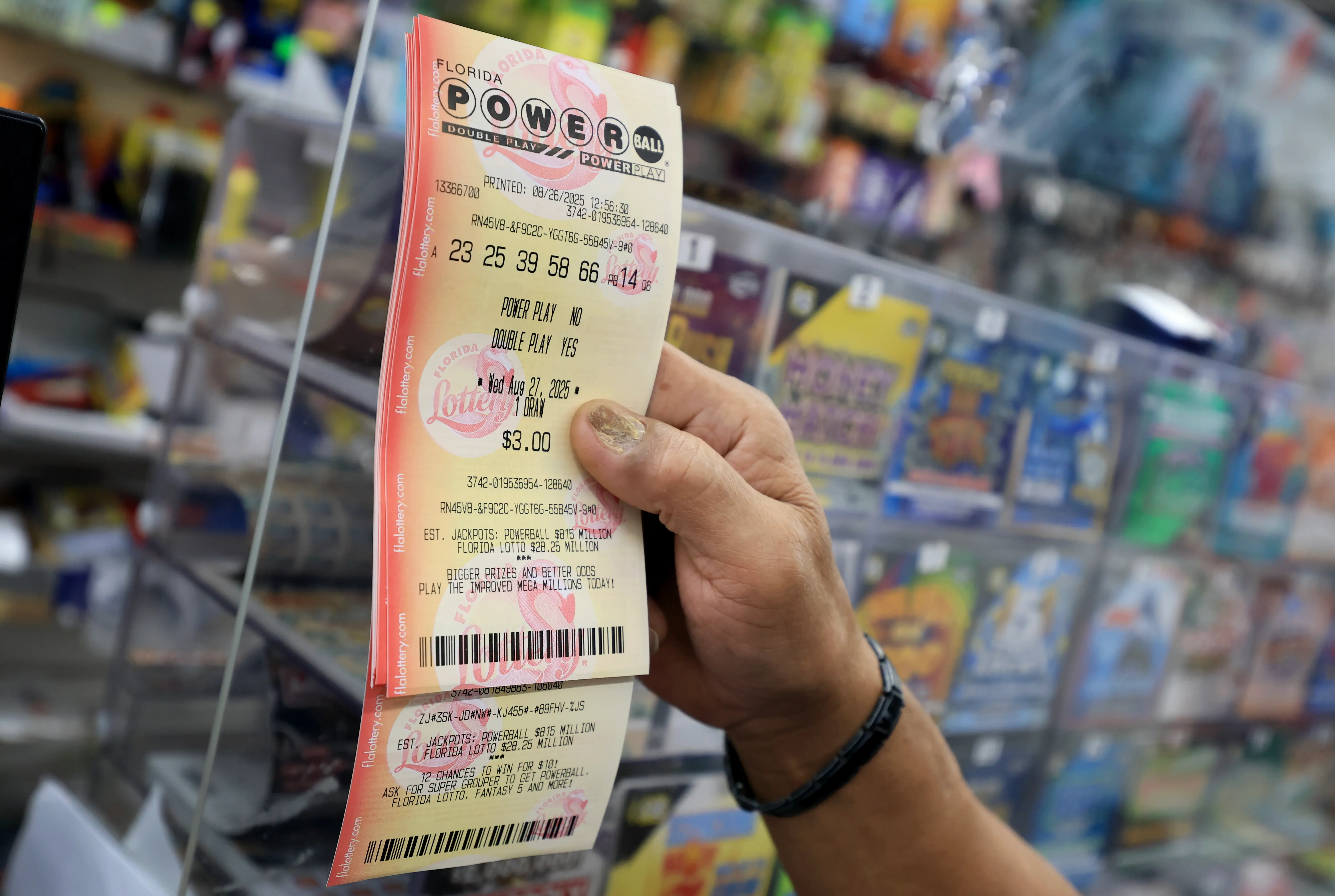 MIAMI, FLORIDA - AUGUST 26:  A customer holds a Powerball lottery ticket after purchasing it at the Downtown Miami Souvenirs store on August 26, 2025 in Miami, Florida. The Powerball jackpot has climbed to $815 million ahead of Wednesday's drawing, making the jackpot the 10th-largest in Powerball history. (Photo by Joe Raedle/Getty Images)