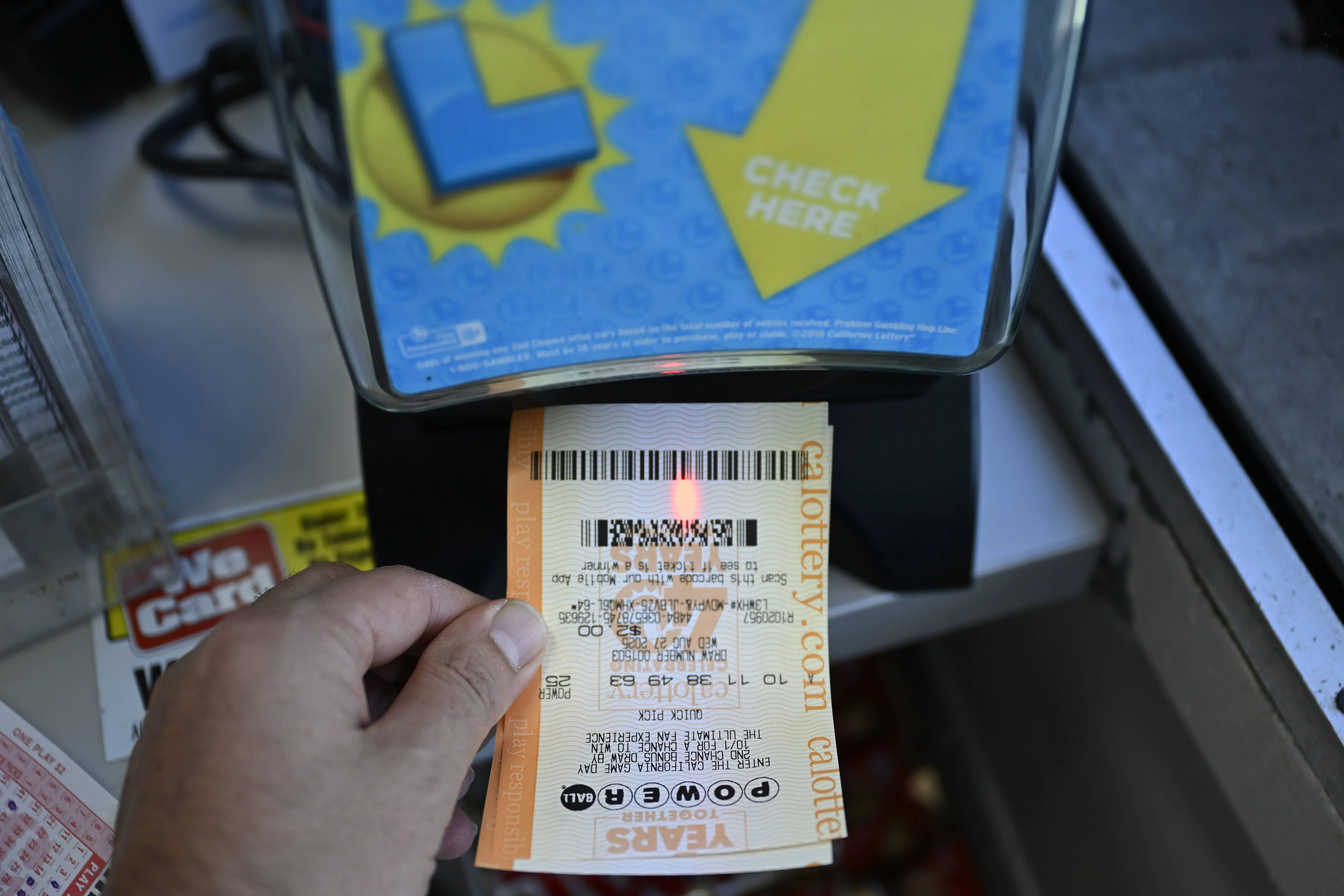 CALIFORNIA, UNITED STATES - AUGUST 28: A man checks his Powerball lottery ticket as U.S. Powerball jackpot grows $950 million, in Foster City, California, United States on August 28, 2025. (Photo by Tayfun Coskun /Anadolu via Getty Images)