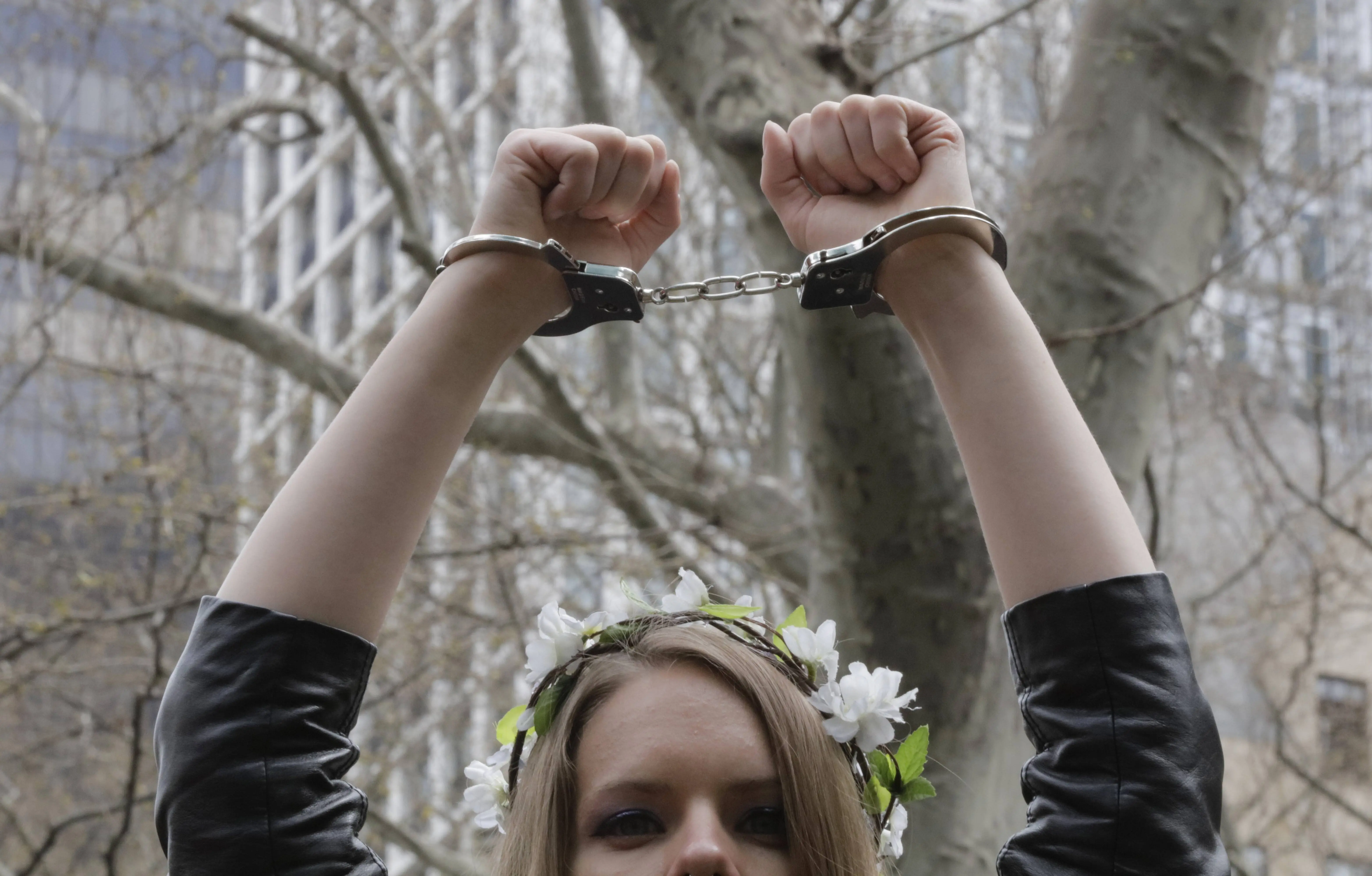 A young woman wearing a flower garlands holds her handcuffed arms skyward during a march, corresponding with Tax Day, demanding that United States President Donald Trump release his tax returns, New York City, New York, April 15, 2017. (Photo via EuropaNewswire/Gado/Getty Images).