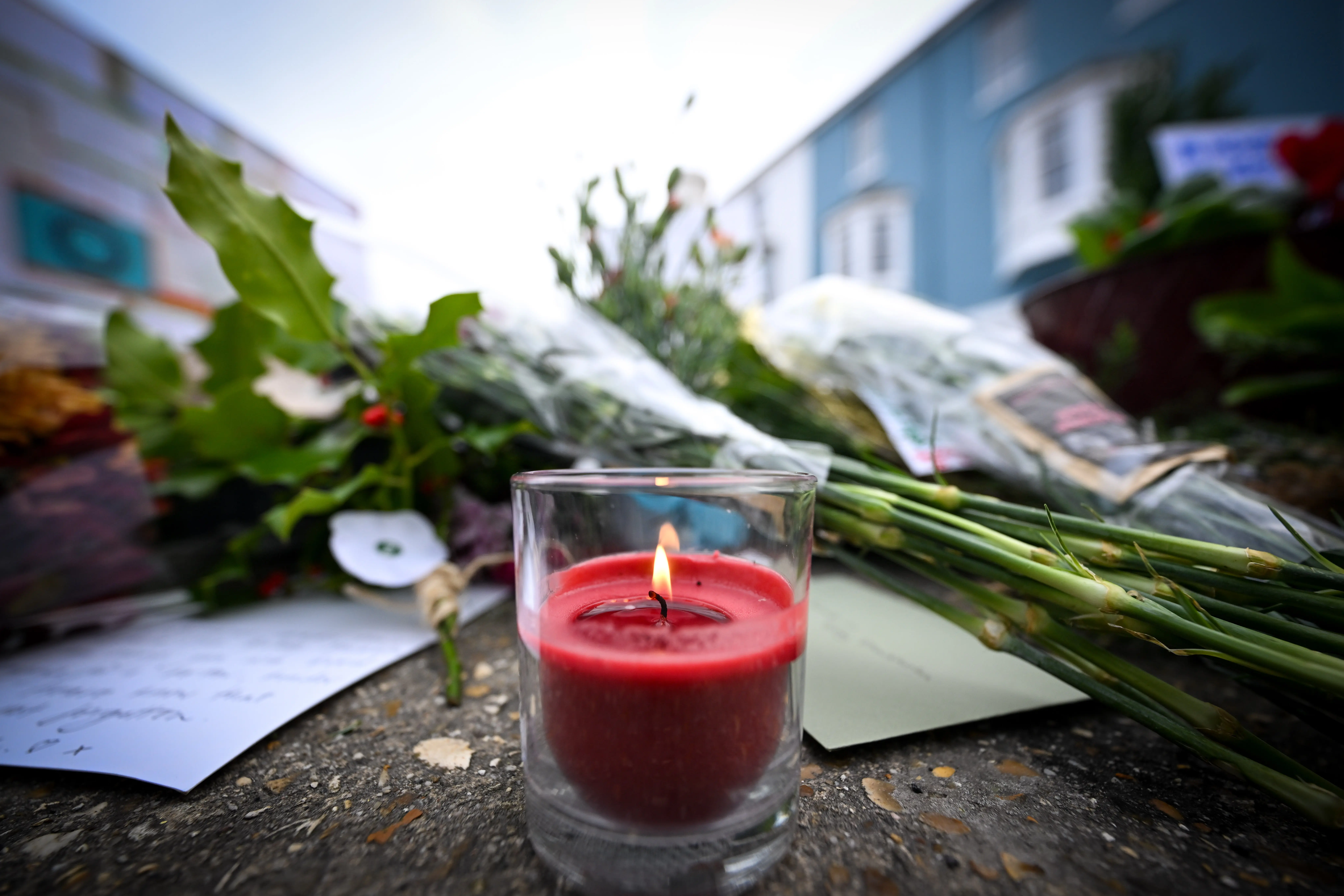 PORTLAND, ENGLAND - DECEMBER 15: A candle is placed with the flowers at the vigil for the deceased asylum seeker, outside Portland Port, on December 15, 2023 in Portland, England. Stand Up to Racism Dorset and Cate4Calais called the vigil and a minute's silence for the unnamed man to pay tribute to him and the struggles he faced in his life. The event organisers say cards and messages "will give support and solidarity to the over 300 refugees on the barge facing the stress of this death on top of their ongoing fears and concerns living in what many describe as like a prison". They will also call for the Bibby Stockholm to be axed, improve mental health for residents on board and make changes to the asylum system. (Photo by Finnbarr Webster/Getty Images)