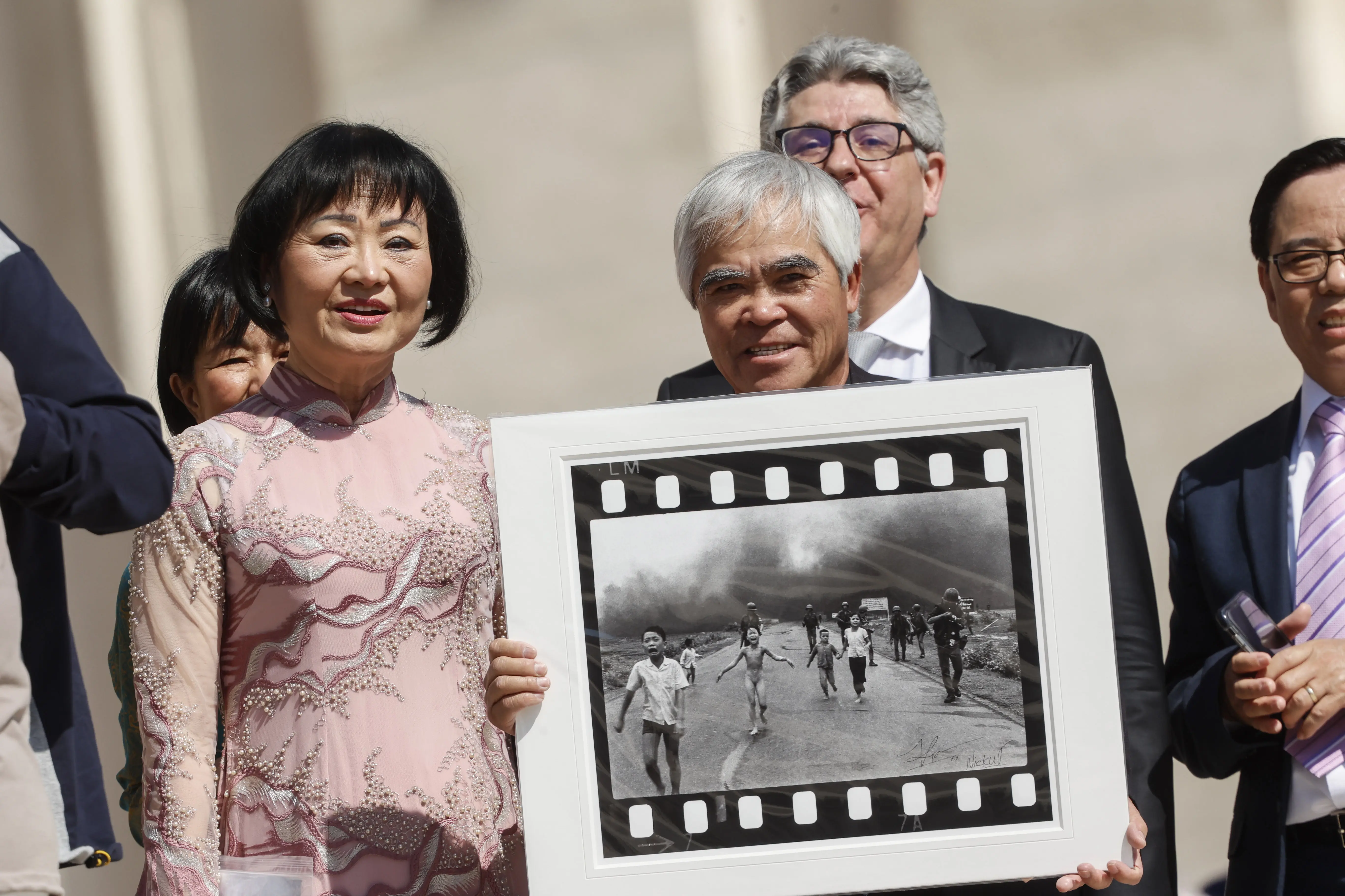 VATICAN, VATICAN CITY, MAY 11: Pulitzer Prize-winning photographer Nick Ut (R), flanked by Kim Phuc, known as the "Napalm Girl", shows his Vietnam war iconic photo as they wait to meet Pope Francis at the end of his weekly general audience in St. Peter's Square, Vatican City, Vatican on May 11, 2022. (Photo by Riccardo De Luca/Anadolu Agency via Getty Images)