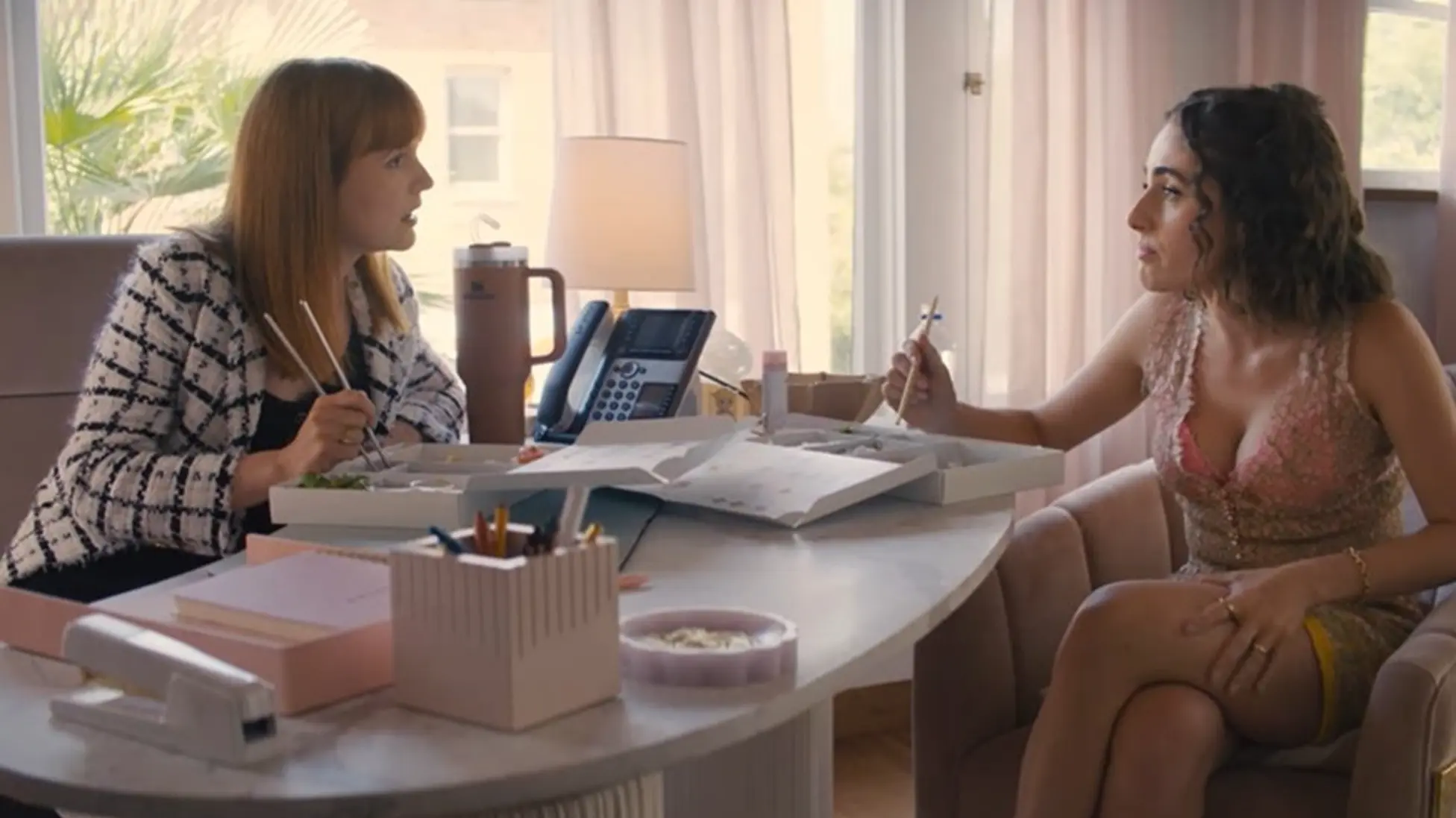 Maia and Alyssa share boxed lunches in the office as the dinner invite takes shape in I Love LA season 1 episode 5. Image via HBO Max.