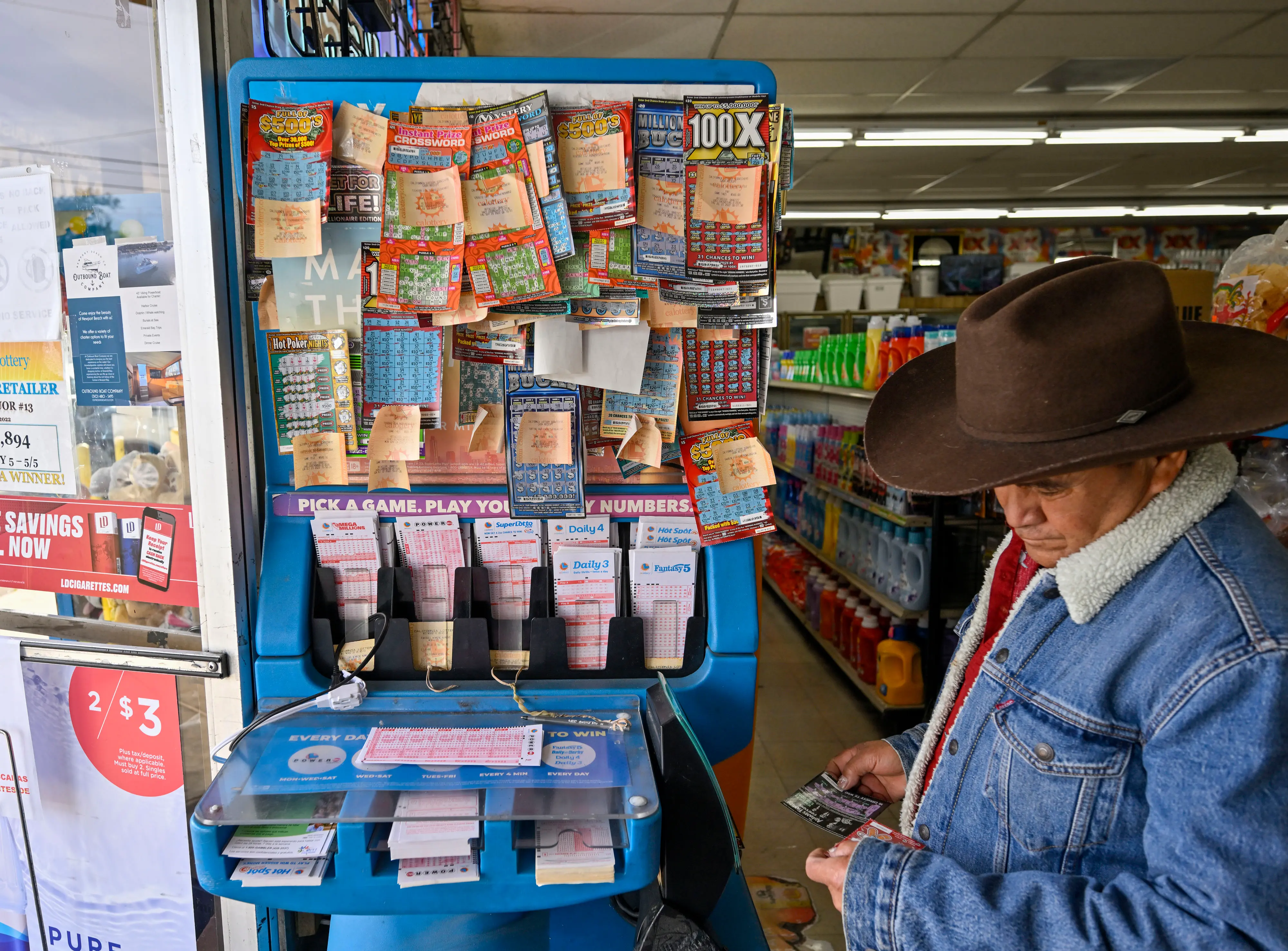 Garden Grove, CA - November 02: Alberto Lara checks for winning scratchers at the lottery station inside ABC Liquor in Garden Grove, CA, on Wednesday, November 2, 2022. The Powerball prize soared to $1.2 billion after no winners were found Monday. (Photo by Jeff Gritchen/MediaNews Group/Orange County Register via Getty Images)