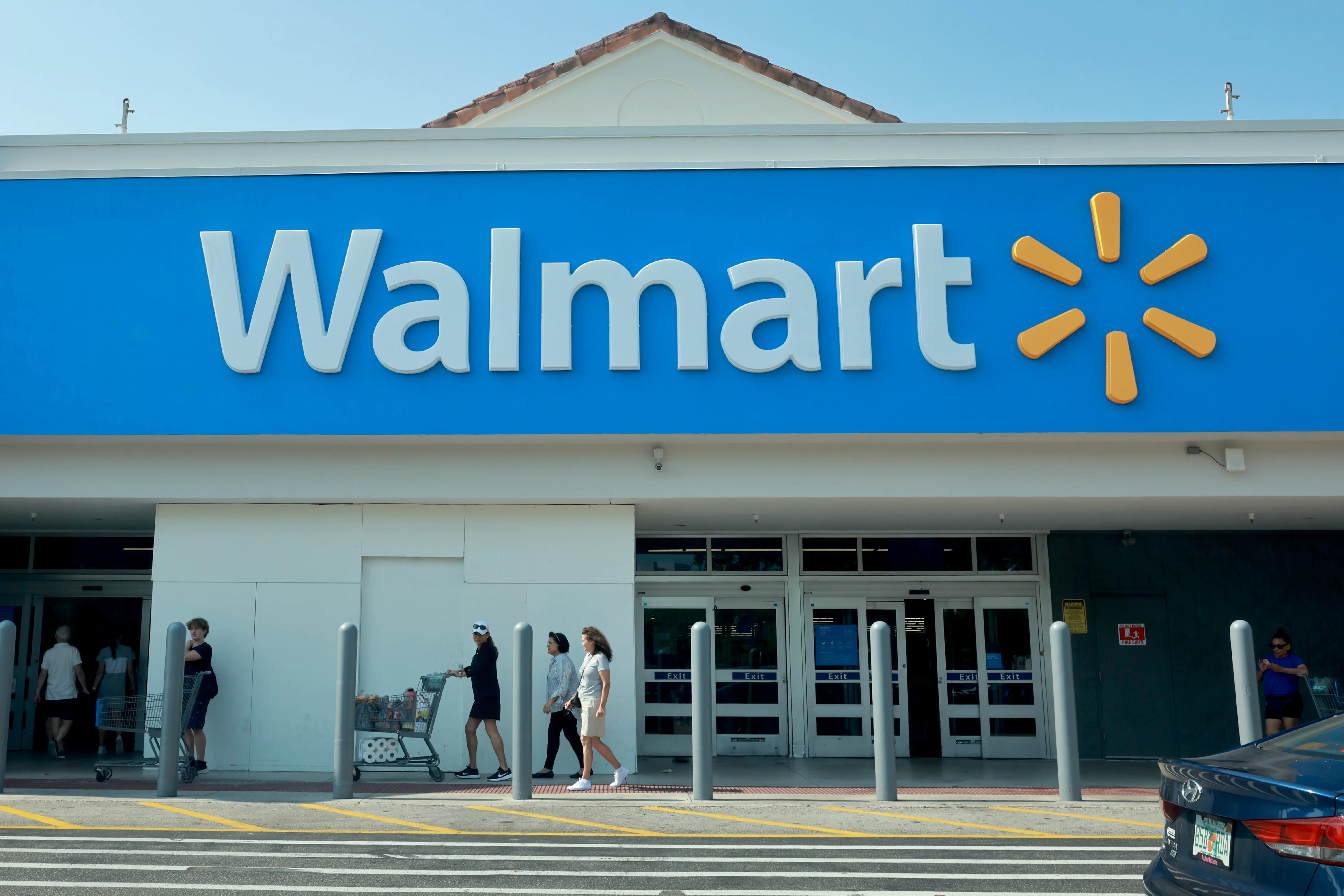 People walk near the entrance to a Walmart store on May 14, 2024 in Miami, Florida. Walmart announced that it will eliminate several hundred corporate jobs and relocate most of its remaining remote office staff. (Photo by Joe Raedle/Getty Images)