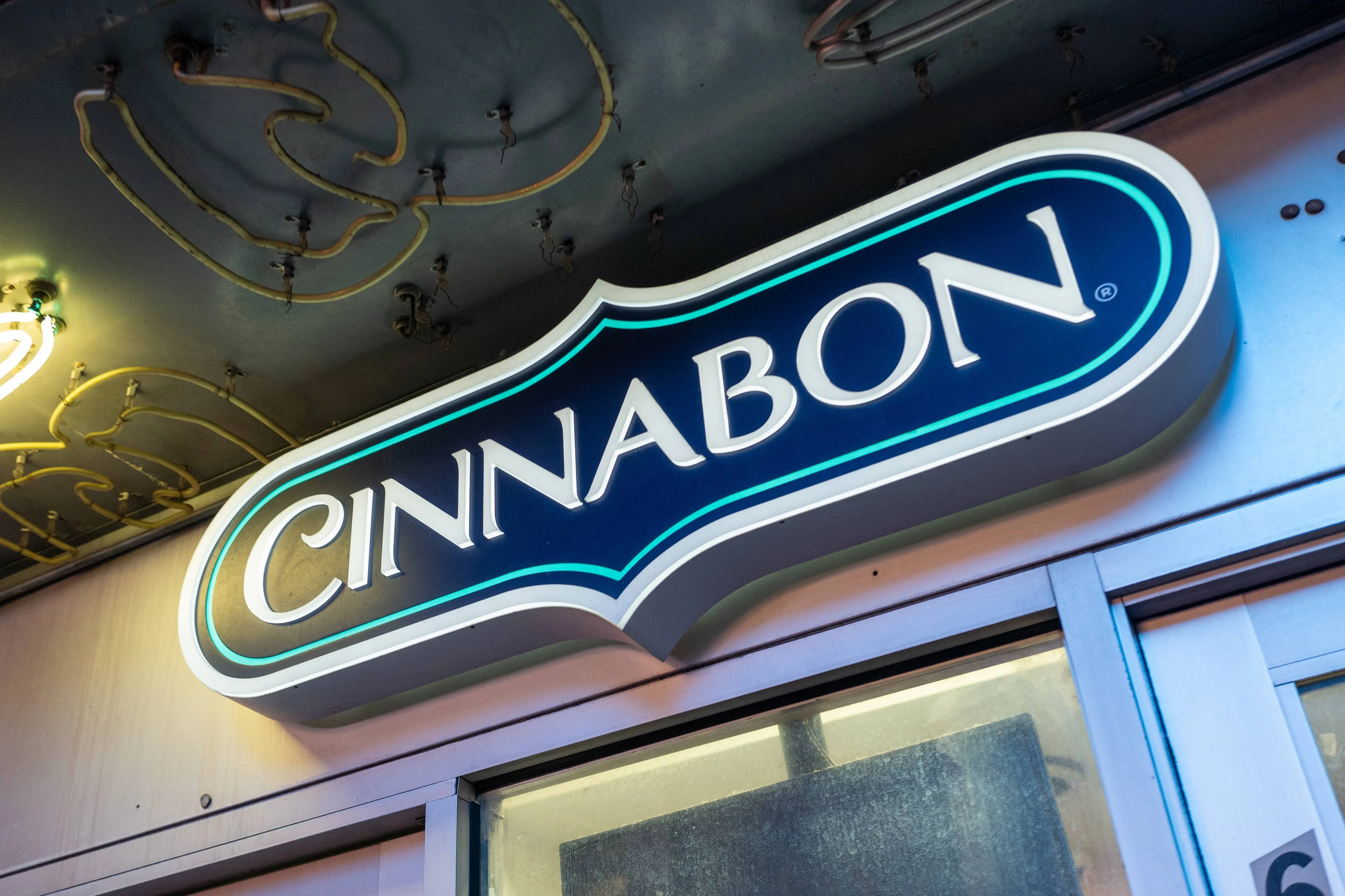 Close-up of a Cinnabon storefront sign with illuminated lettering, New York City, New York, October 20, 2024. (Photo by Smith Collection/Gado/Getty Images)