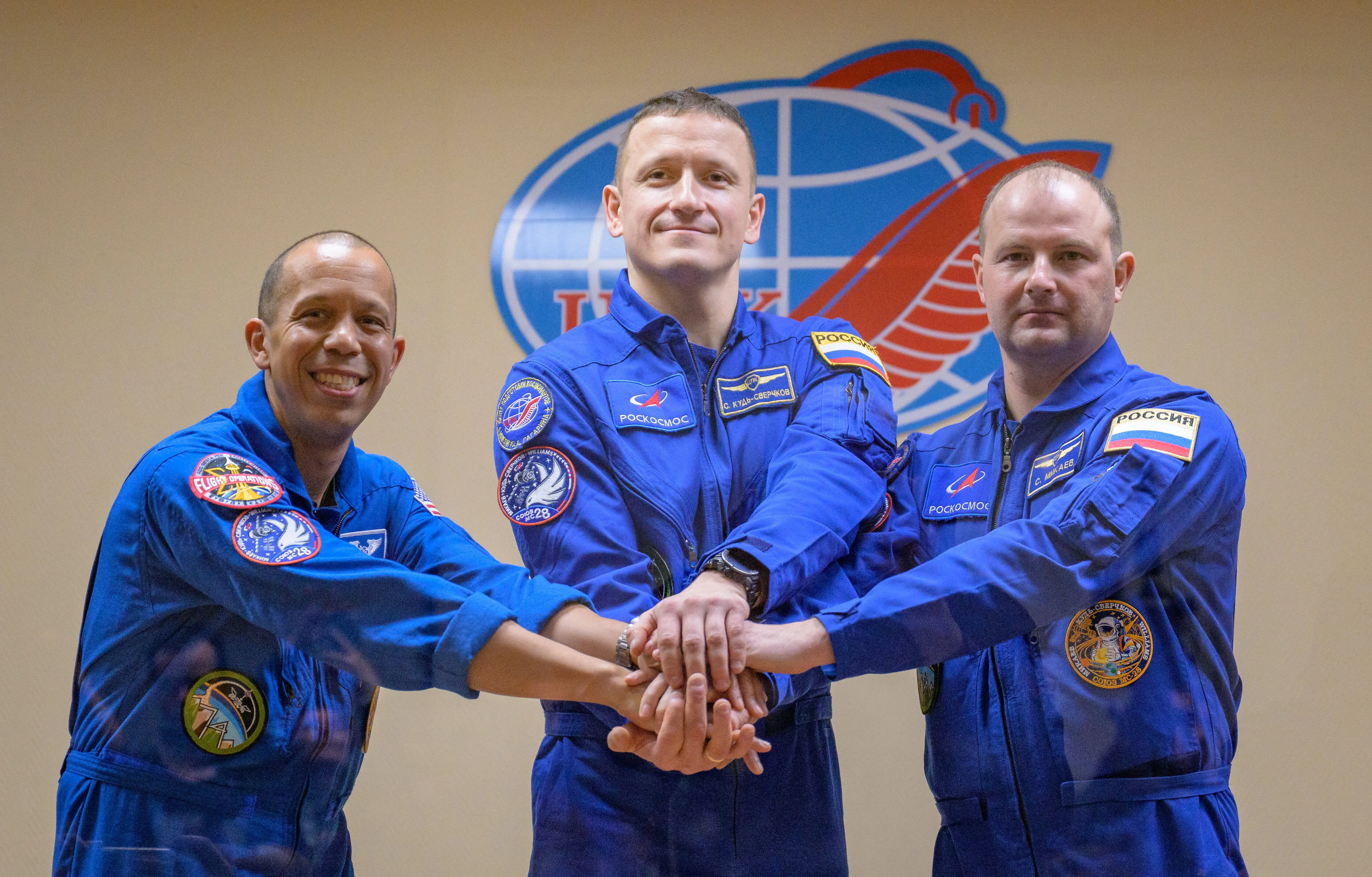 BAIKONUR, KAZAKHSTAN - NOVEMBER 26: (EDITOR’S NOTE: This Handout image was provided by a third-party organization and may not adhere to Getty Images’ editorial policy.) In this handout image provided by NASA, astronaut Chris Williams, left, and Roscosmos cosmonauts Sergey Kud-Sverchkov, and Sergei Mikaev, right, are seen in quarantine, behind glass, during a press conference at the Cosmonaut Hotel on November 26, 2025 in Baikonur, Kazakhstan. Expedition 74 crewmembers: NASA astronaut Chris Williams, Roscosmos cosmonauts Sergey Kud-Sverchkov and Sergei Mikaev, are scheduled to launch aboard their Soyuz MS-28 spacecraft on November 27. (Photo by Bill Ingalls/NASA via Getty Images)