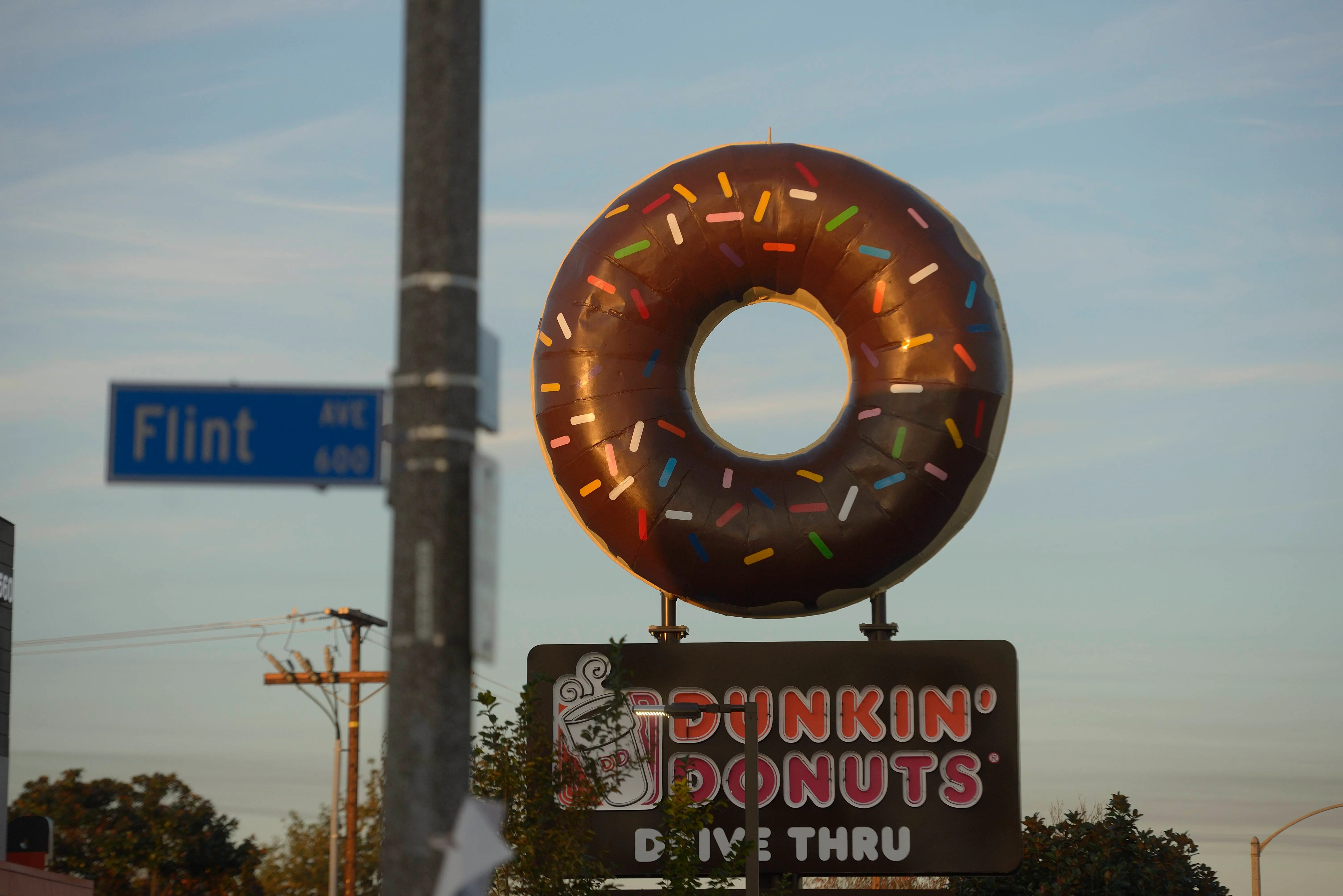 A giant donut sits atop a Dunkin' Donuts sign on Seventh Street in Long Beach (Image via Getty)