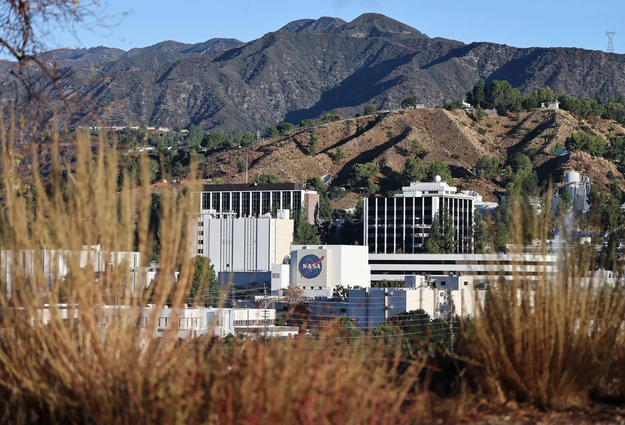 The NASA logo is displayed at NASA’s Jet Propulsion Laboratory on October 15, 2025 in La Cañada Flintridge, California. Around 550 people, or over ten percent of the famed lab’s workforce, are being laid off as part of an ongoing reorganization following two rounds of large layoffs last year. Layoffs at the laboratory, which is funded by NASA and managed by CalTech, are not related to the federal government shutdown (Image via Getty)