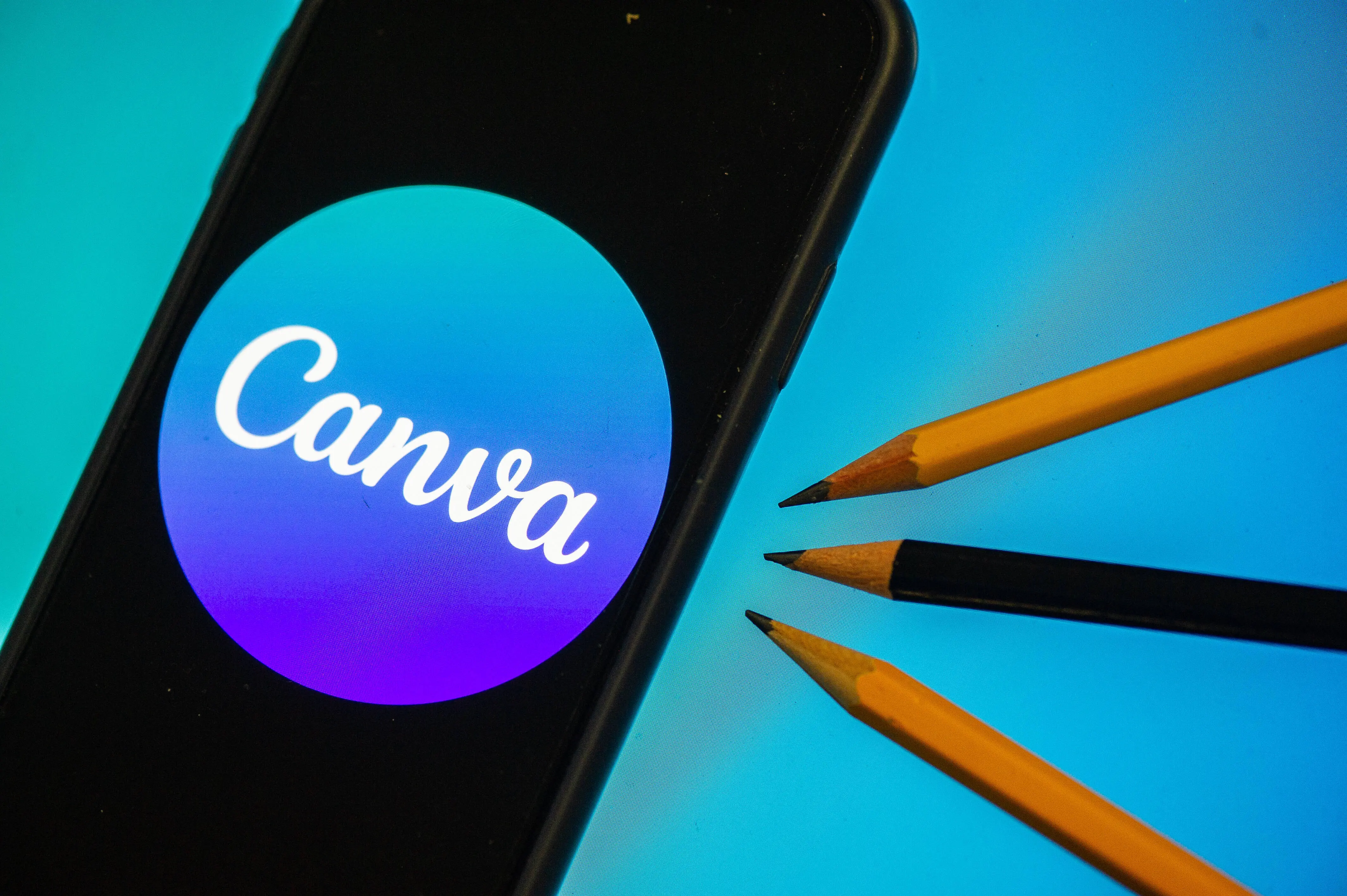 A Canva logo displayed on a smartphone and three pencils are seen in L'Aquila, Italy, on October 4th, 2023. On October 4th Canva launched "Magic Studio", its new design platoform powered by AI (Artificial Intelligence).  (Photo by Lorenzo Di Cola/NurPhoto via Getty Images)