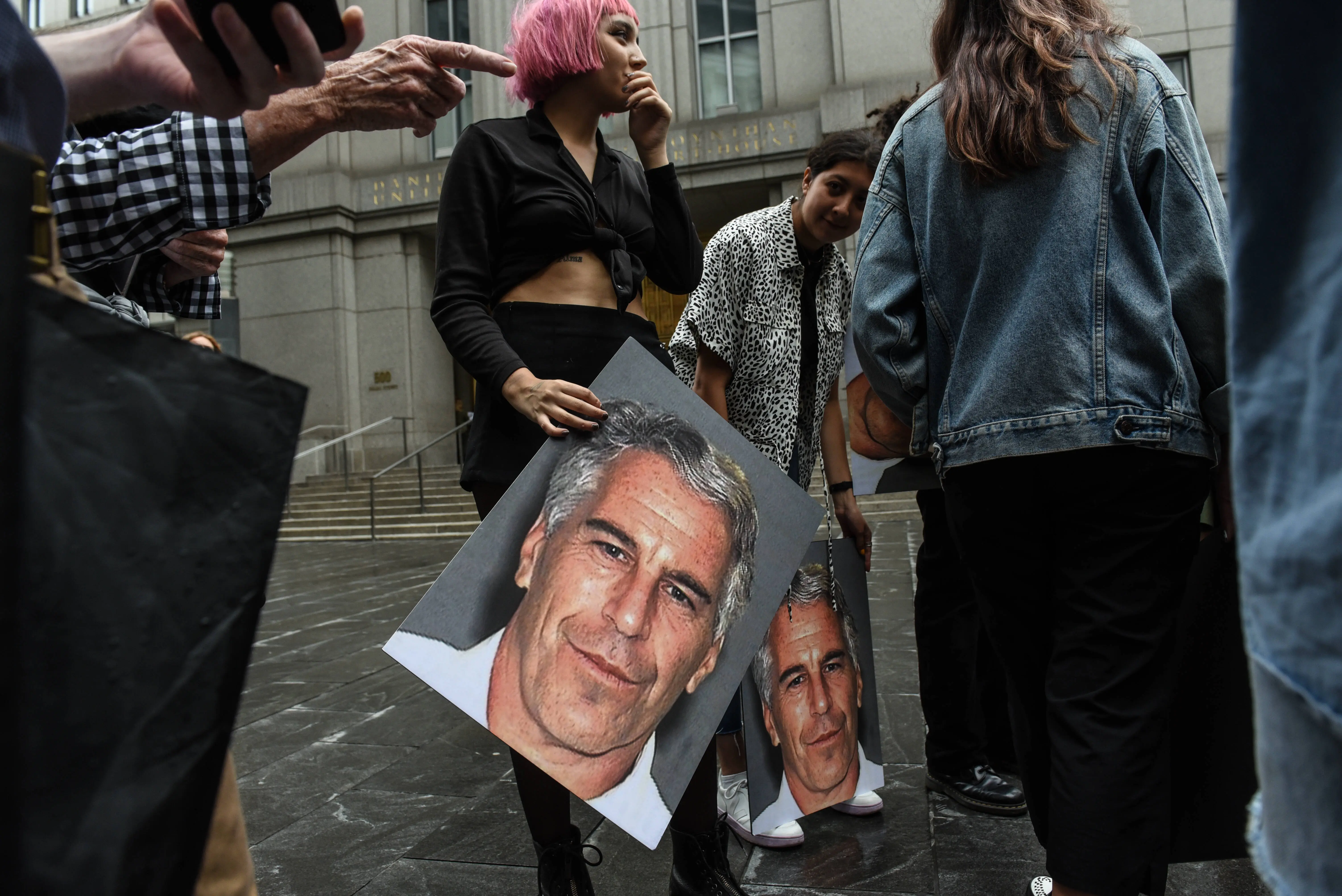 A protest group called "Hot Mess" hold up signs of Jeffrey Epstein in front of the Federal courthouse (Image via Getty)