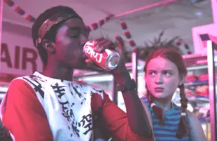 Max Mayfield (Sadie Sink) looks on as Lucas Sinclair (Caleb McLaughlin) enjoys the clean crisp taste of New Coke in Stranger Things 3. (Netflix)