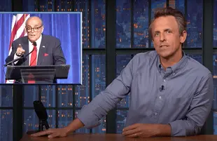 Seth Meyers next to a graphic of Rudy Giuliani giving a speech at a 9/11 dinner (Photo: NBC)