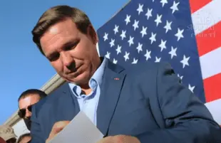Ron DeSantis signs something at a campaign rally (Photo: CBS)