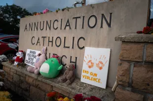 People leave flowers and other mementoes in front of Annunciation Catholic Church, a rapidly growing memorial to the victims of yesterday's shooting on August 28, 2025 in Minneapolis, Minnesota (Image via Getty)