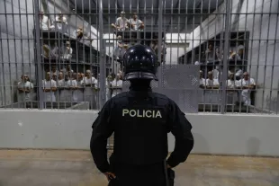 An officer in riot gear stands on patrol inside a cell at CECOT in Tecoluca (Image via Getty)
