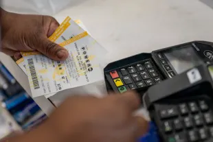 HOUSTON, TEXAS - JULY 28: A person pays for a Mega Millions lottery ticket on July 28, 2022 in Houston City. The lottery jackpot has increased to $1 Billion after not being matched Tuesday night. (Photo by Brandon Bell/Getty Images)
