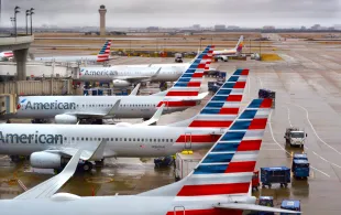 American Airlines passenger jets parked at their gates on a rainy morning at Dallas/Fort Worth International Airport which serves the Dallas/Fort Worth, Texas, metroplex area in Texas (Image via Getty)