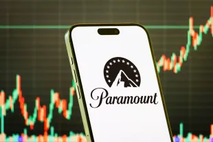 CHONGQING, CHINA - JULY 29: In this photo illustration, a smartphone displays the logo of Paramount Global (NASDAQ: PARA), a leading global media and entertainment company, in front of a screen showing the company's latest stock market chart on July 29, 2025 in Chongqing, China. (Photo illustration by Cheng Xin/Getty Images)