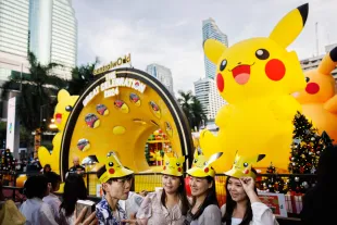 BANGKOK, THAILAND - NOVEMBER 27: Pokemon fans wear Pikachu hats and take selfies in front of a giant inflatable Pikachu at Central World Shopping Mall during a holiday kick off event on November 27, 2023 in Bangkok, Thailand. Featuring the largest Pokemon takeover in Southeast Asia, Central World Shopping Center hosts its "Light Up Christmas Tree Celebration" to kick off the holiday season. The celebration includes 30 dancing Pikachus, a 15-meter-tall inflatable Pikachu, and other Pokemon characters placed around Thailand's tallest Christmas tree, which is decorated with thunderbolts. (Photo by Lauren DeCicca/Getty Images)