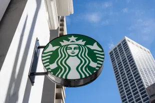 Starbucks coffee shop sign mounted on an exterior wall with a high-rise building in the background, San Francisco, California, February 21, 2025. (Photo by Smith Collection/Gado/Getty Images)