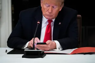 President Donald J. Trump uses his cellphone as he participates in a roundtable discussion with Governors. (Photo by Jabin Botsford/The Washington Post via Getty Images)