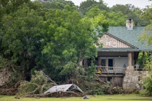 Debris is piled up at the entrance to Camp Mystic on July 07, 2025 in Hunt, Texas (Image via Getty)