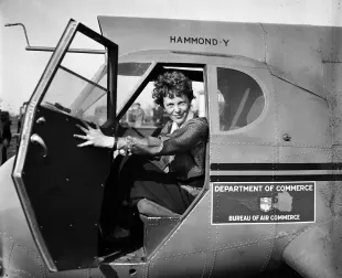 American aviatrix and pioneer Amelia Earhart (1897 - 1937) holds open the door of a Stearman Hammond Y-1 monoplane (Image via Getty)