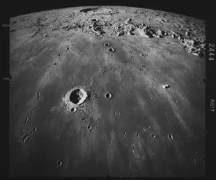 Image of the lunar surface, looking south across Mare Imbrium, with the crater Copernicus (58 miles in diameter) visible in the distance, in an image of the lunar surface taken during the Apollo 17, 7th to 19th December 1972. Crater Pytheas (12 miles in diameter) is visible in the foreground, with several chains of small craters beyond, these are oriented toward Copernicus and are secondary craters produced by material ejected when Copernicus formed. (Photo by Space Frontiers/Archive Photos/Hulton Archive/Getty Images)