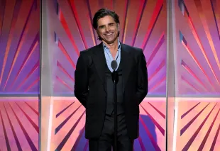 BEVERLY HILLS, CALIFORNIA - FEBRUARY 08: John Stamos speaks onstage during AARP's Annual Movies For Grownups Awards at the Beverly Wilshire, A Four Seasons Hotel on February 08, 2025 in Beverly Hills, California.  (Photo by Michael Kovac/Getty Images for AARP)