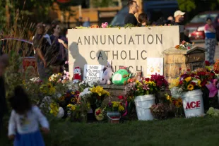 People leave flowers and other mementoes in front of Annunciation Catholic Church, a rapidly growing memorial to the victims of the shooting on August 28, 2025 in Minneapolis, Minnesota. A gunman fired through the windows of the church while students were sitting in pews during a Catholic school Mass, killing two children and injuring at least 17 others. (Photo by Scott Olson/Getty Images)