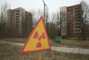 A sign warns of radiation contamination near former apartment buildings on April 9, 2016 in Pripyat, Ukraine. Pripyat, built in the 1970s as a model Soviet city to house the workers and families of the Chernobyl nuclear power plant, now stands abandoned inside the Chernobyl Exclusion Zone, a restricted zone contaminated by radiation from the 1986 meltdown of reactor number four at the nearby Chernobyl plant in the world's worst civilian nuclear accident that spewed radiaoactive fallout across the globe. Authorities evacuated approximately 43,000 people from Pripyat in the days following the disaster and the city, with its high-rise apartment buildings, hospital, shops, schools, restaurants, cultural center and sports facilities, has remained a ghost-town ever since. The world will soon commemorate the 30th anniversary of the April 26, 1986 Chernobyl disaster. Today tour operators bring tourists in small groups to explore certain portions of the exclusion zone.  (Photo by Sean Gallup/Getty Images)