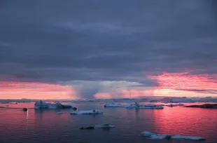 ILULISSAT, GREENLAND - SEPTEMBER 04: The sun sets as rain falls beyond floating ice and icebergs in Disko Bay above the Arctic Circle on September 04, 2021 in Ilulissat, Greenland. 2021 will mark one of the biggest ice melt years for Greenland in recorded history. Researchers from Denmark estimated that in July of this year enough ice melted on the Greenland Ice Sheet to cover the entire state of Florida with two inches of water. According to NASA, Greenland has melted 5 trillion tons of ice over approximately the past 15 years, enough to increase global sea level by nearly an inch. The observations come on the heels of the recent United Nations report on global warming which stated that accelerating climate change is driving an increase in extreme weather events. (Photo by Mario Tama/Getty Images)