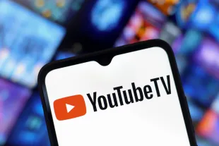 The YouTube TV logo appears on the screen of a smartphone and in the background on the computer screen in Reno, United States, on December 15, 2024. (Photo by Jaque Silva/NurPhoto via Getty Images)