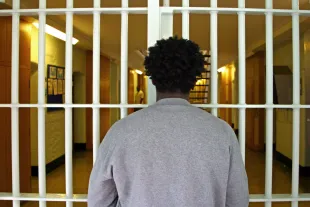 A young black male prisoner waits at a security partition gate in the D wing of Wandsworth prison. HMP Wandsworth in South West London was built in 1851 and is one of the largest prisons in Western Europe. It has a capacity of 1456 prisoners. (Photo by Andrew Aitchison/In Pictures Ltd./Corbis via Getty Images)