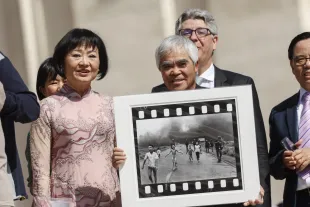 VATICAN, VATICAN CITY, MAY 11: Pulitzer Prize-winning photographer Nick Ut (R), flanked by Kim Phuc, known as the "Napalm Girl", shows his Vietnam war iconic photo as they wait to meet Pope Francis at the end of his weekly general audience in St. Peter's Square, Vatican City, Vatican on May 11, 2022. (Photo by Riccardo De Luca/Anadolu Agency via Getty Images)