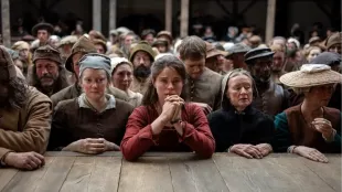 Jessie Buckley as Agnes clasps her hands in the Globe pit as the crowd leans toward the stage during Hamlet’s final moments. Image via Youtube/@Focus Features