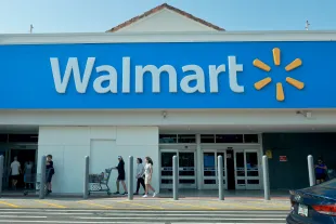 People walk near the entrance to a Walmart store on May 14, 2024 in Miami, Florida. Walmart announced that it will eliminate several hundred corporate jobs and relocate most of its remaining remote office staff. (Photo by Joe Raedle/Getty Images)